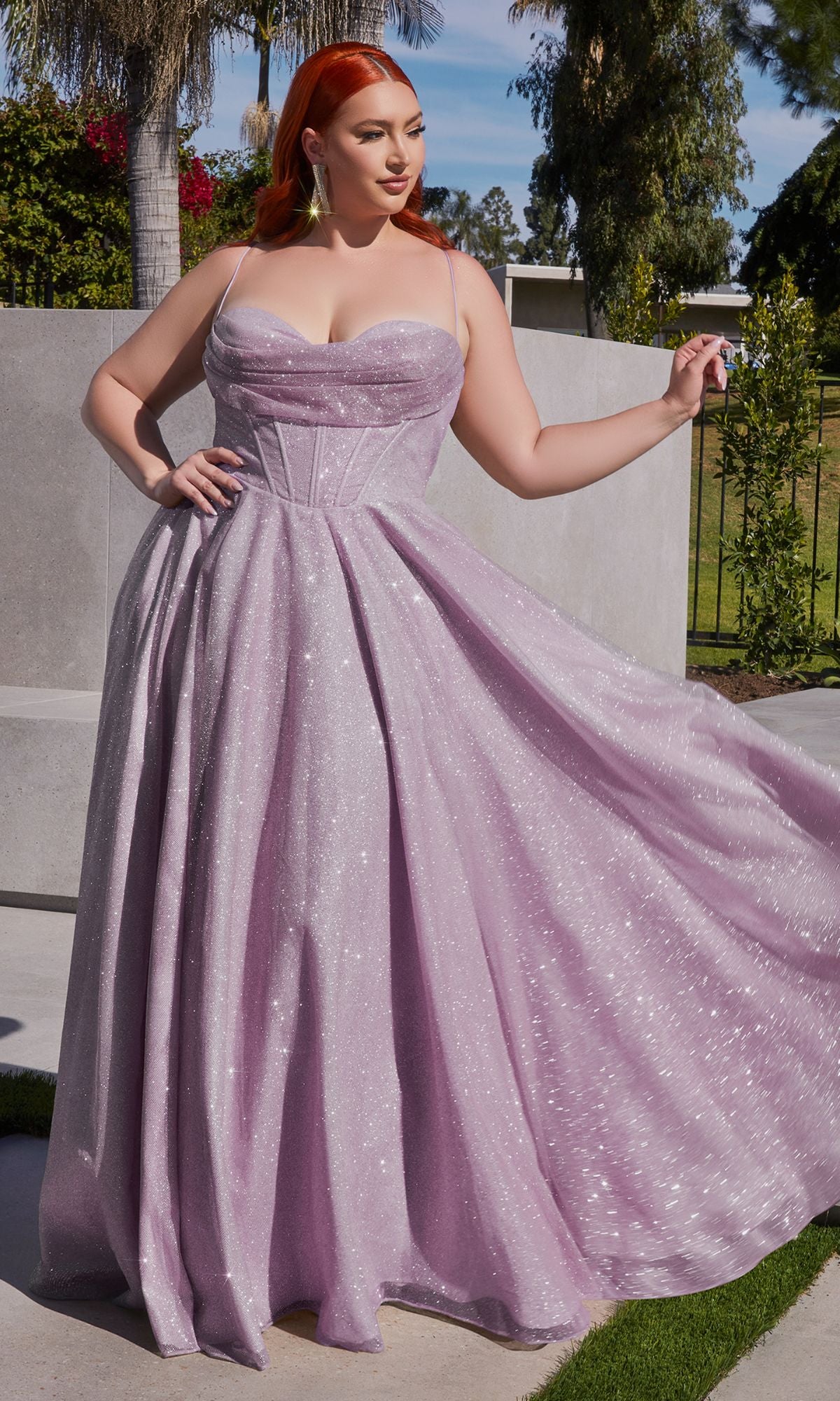 A red-haired woman poses outdoors by concrete steps and greenery, wearing the Plus-Size Long Glitter Prom Dress CD252C in sparkling lavender.
