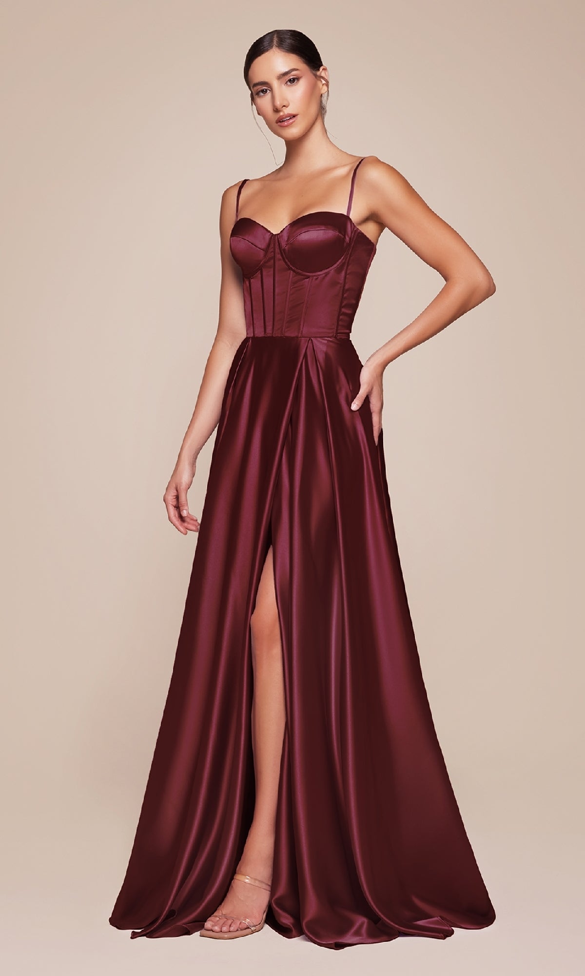 A woman stands against a plain beige background wearing the Ladivine CD337 Long Sweetheart A-Line Prom Dress—a sleeveless, floor-length burgundy gown featuring a corset bodice and thigh-high slit.