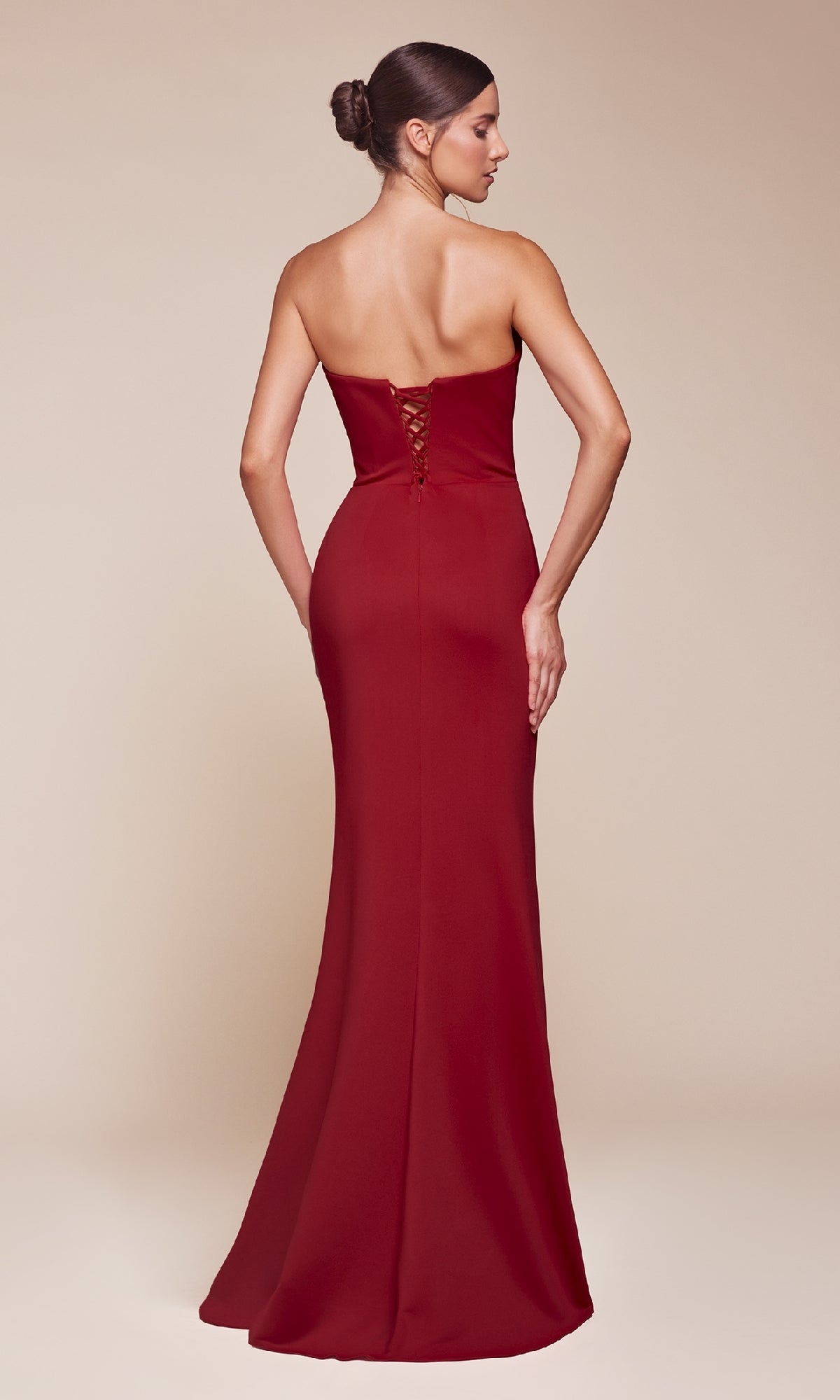 A woman faces away from the camera, showcasing the Ladivine CD355—a strapless, floor-length red prom gown with a fitted silhouette and elegant lace-up back detail.