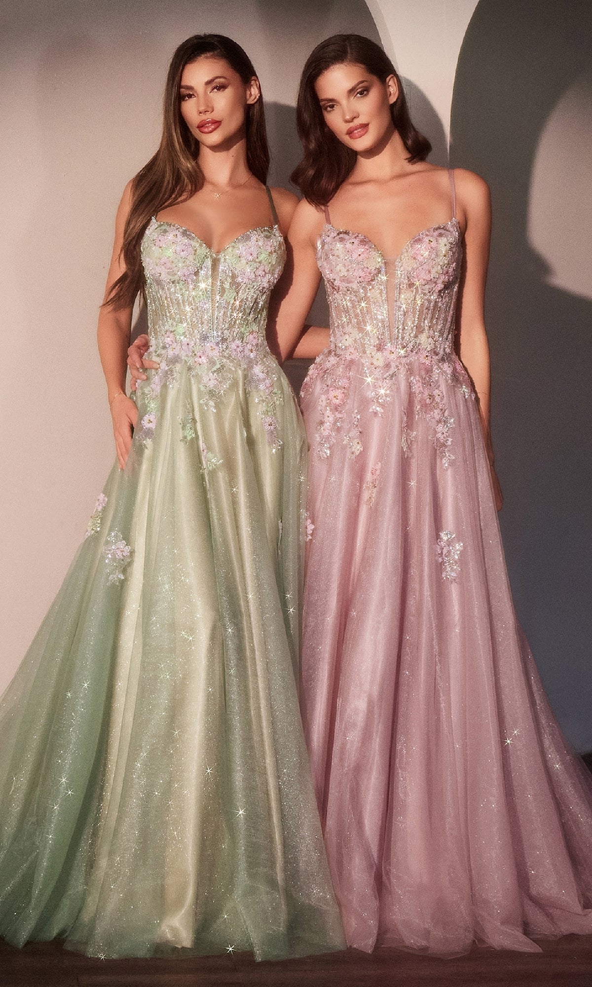Two women stand side by side in the Ladivine CD740 long glitter-tulle prom dress—one in light green, one in light pink—both with spaghetti straps, beaded floral appliques, and sparkling overlays for an enchanting look.