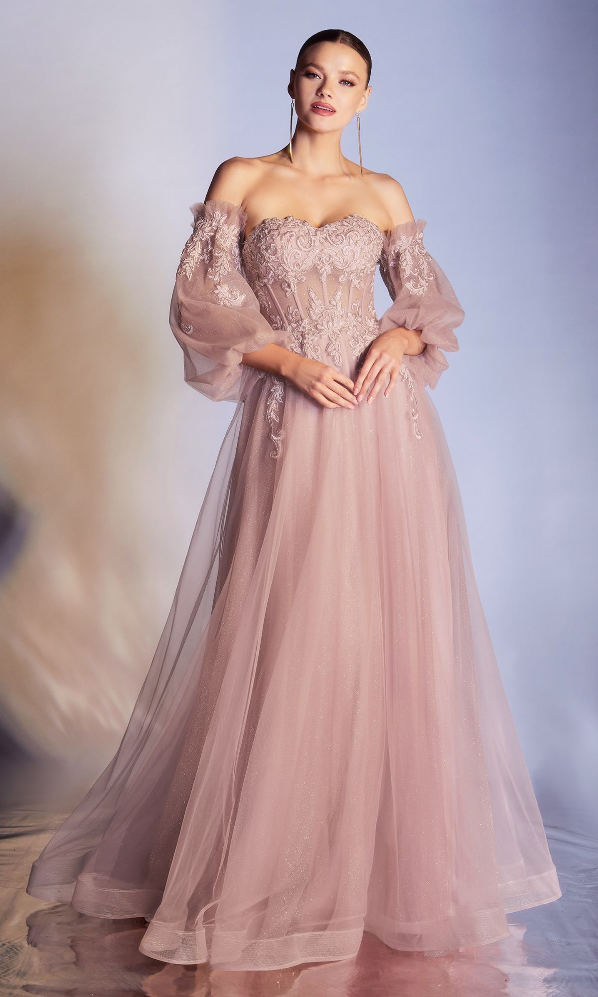 A woman in the Strapless Puff-Sleeve Long Prom Dress CD948, featuring a blush pink hue, removable puff sleeves, lace bodice details, and a flowing tulle skirt, stands against a soft gradient background.