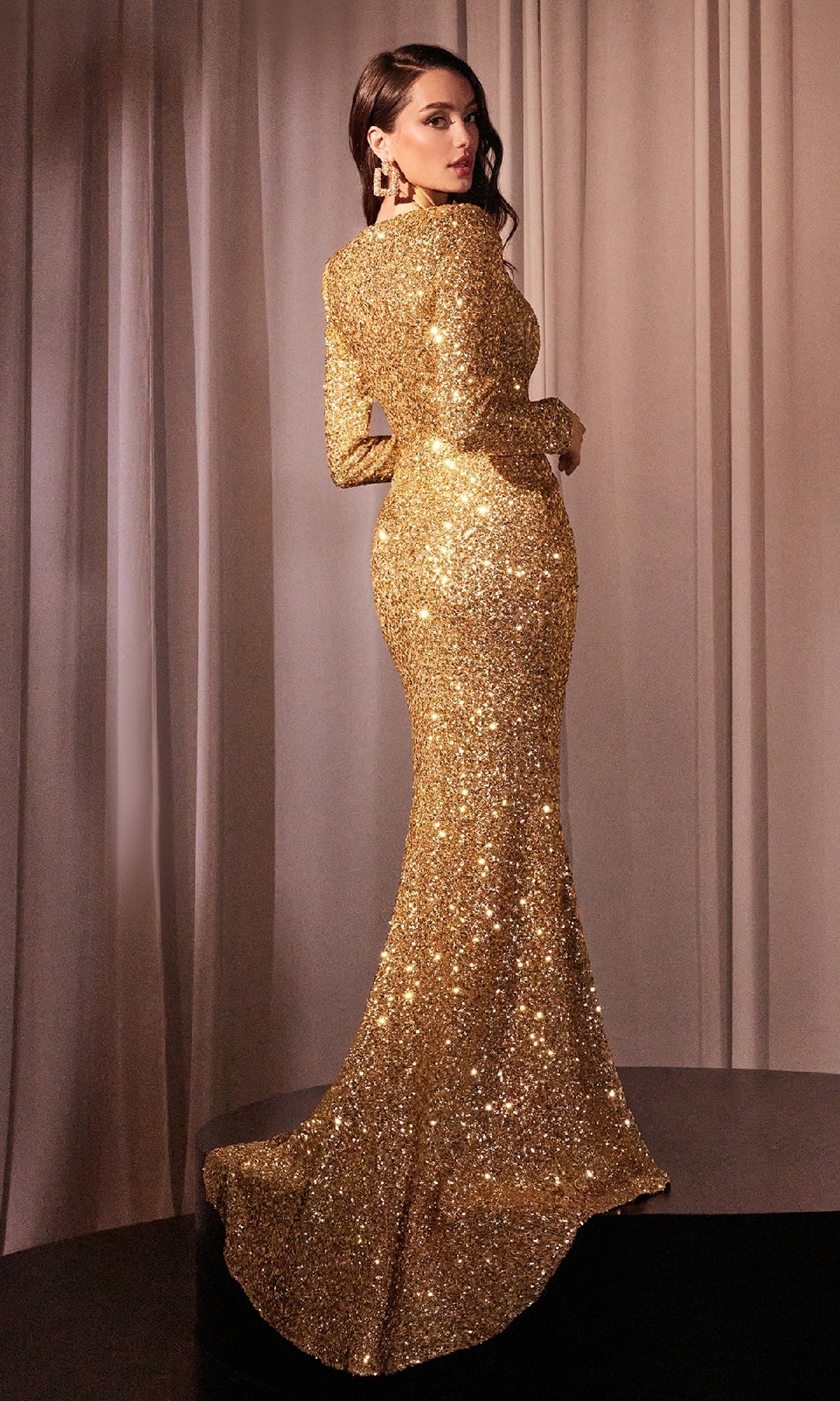 A woman stands on a platform in front of beige curtains, wearing the Ladivine CH054 Long Sleeve Long Formal Dress with a fitted silhouette and sequin details.