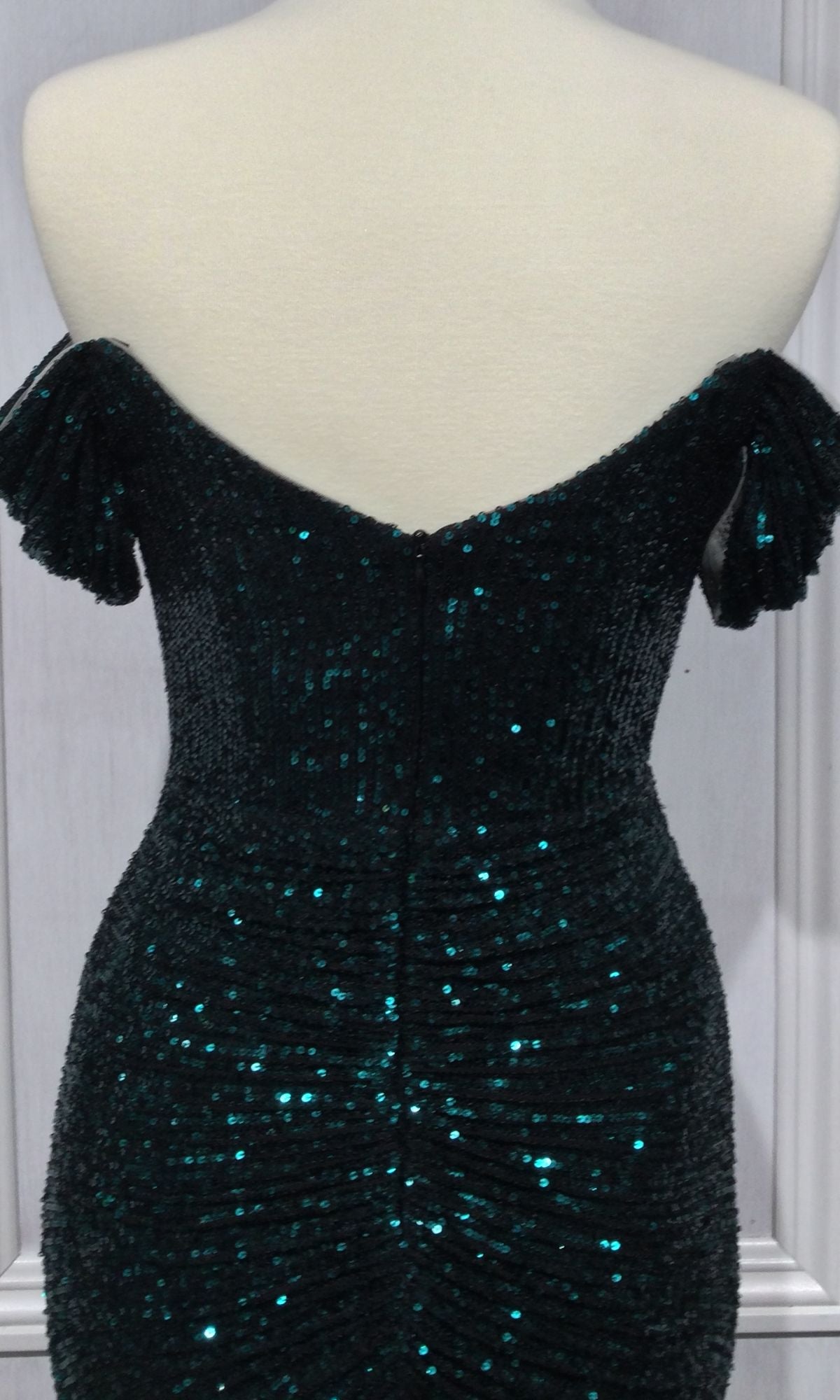 The Off-Shoulder Long Ruched Sequin Prom Dress CH144, under $150, is displayed on a mannequin in dark green with a fitted back and subtle ruched details.