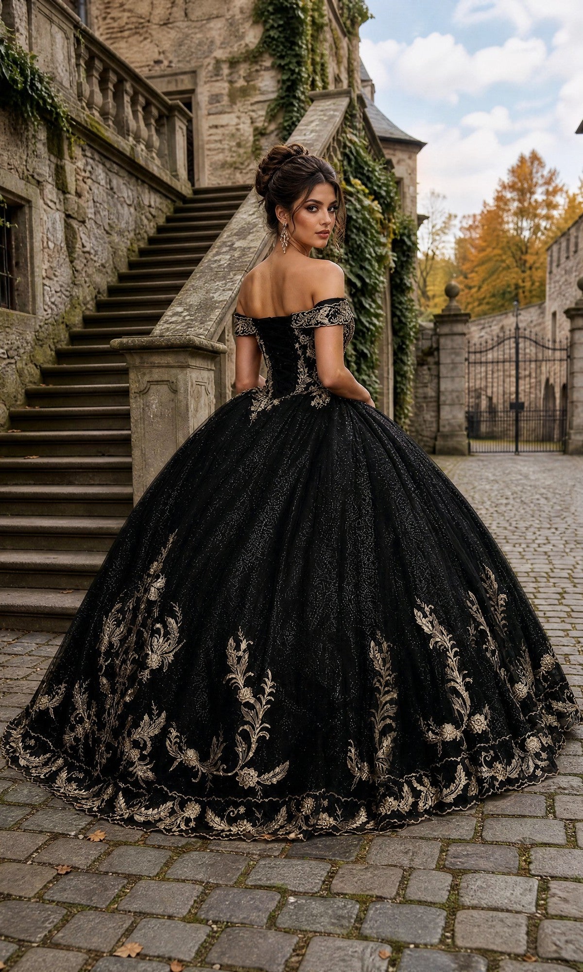 A woman wearing the Quinceanera Dress CHF3006 By Chicas, featuring gold embroidery and an off-the-shoulder design, stands on a stone pathway near stairs and old stone buildings.