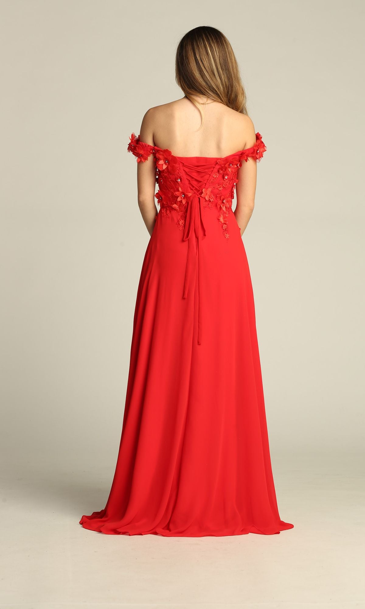 A woman stands with her back to the camera in the Chicas CHF3059 Off-Shoulder Long A-Line Prom Dress, featuring floral details, a lace-up back, and a gracefully flowing floor-length skirt.