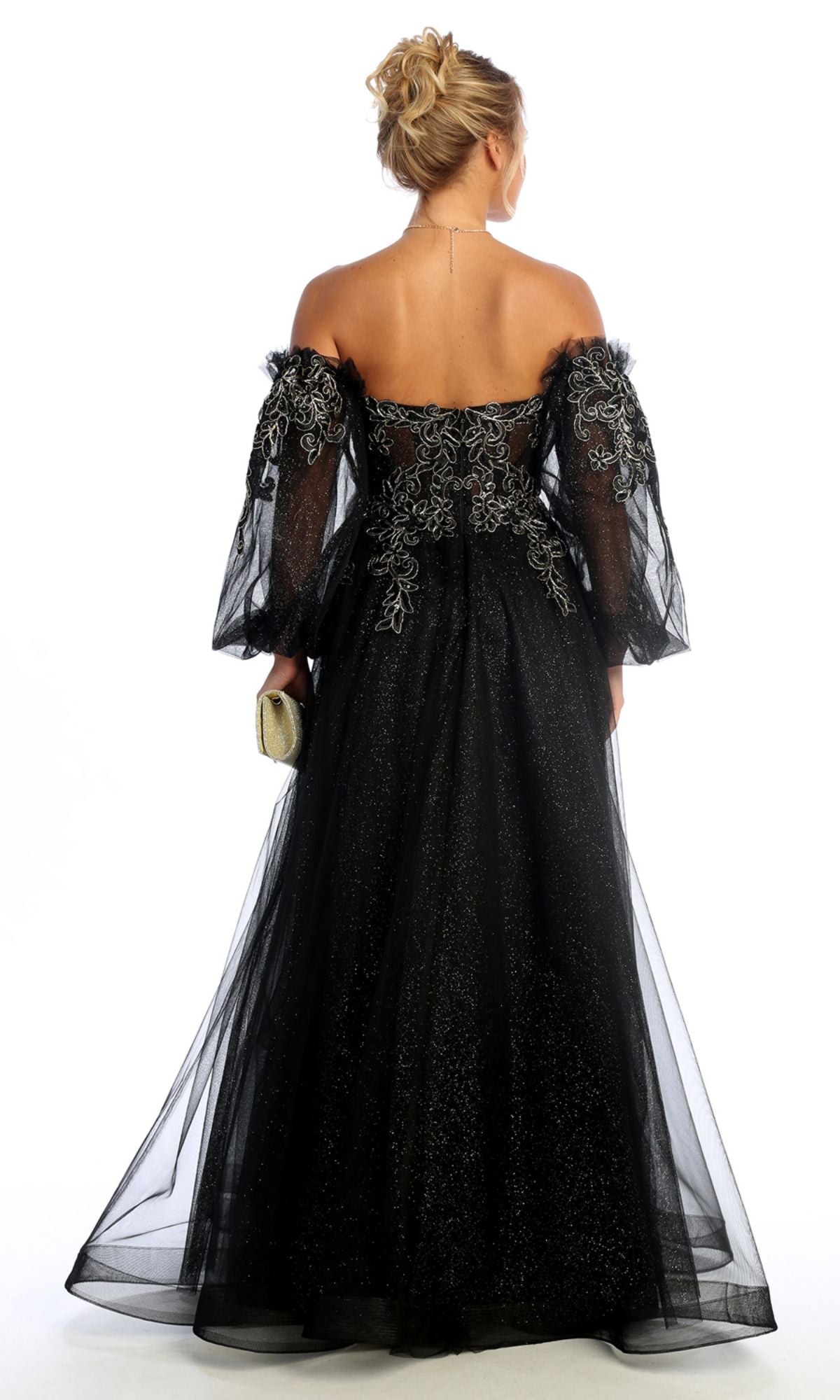 A woman in the Chicas CHF3093 Long Sleeve Long A-Line Prom Dress with sheer sleeves and embroidered details stands facing away, holding a small clutch.