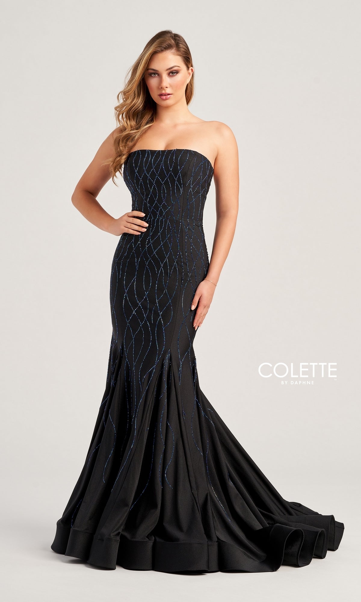 A woman stands against a plain light background wearing the Colette Strapless Long Glitter Prom Dress CL5106, featuring blue glitter print patterns and a mermaid silhouette.