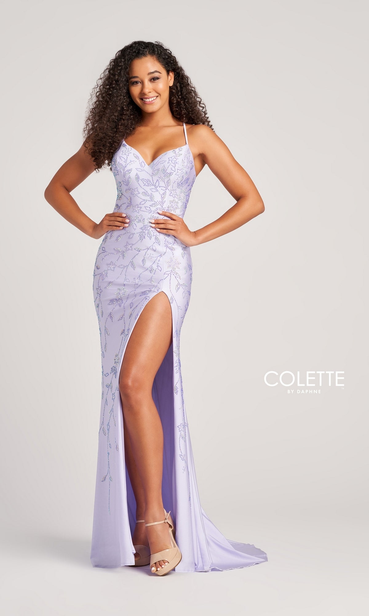 A woman poses against a plain background in the Glitter-Print Long Colette Prom Dress CL5110, a light purple sleeveless gown featuring a thigh-high slit and nude heels. The text