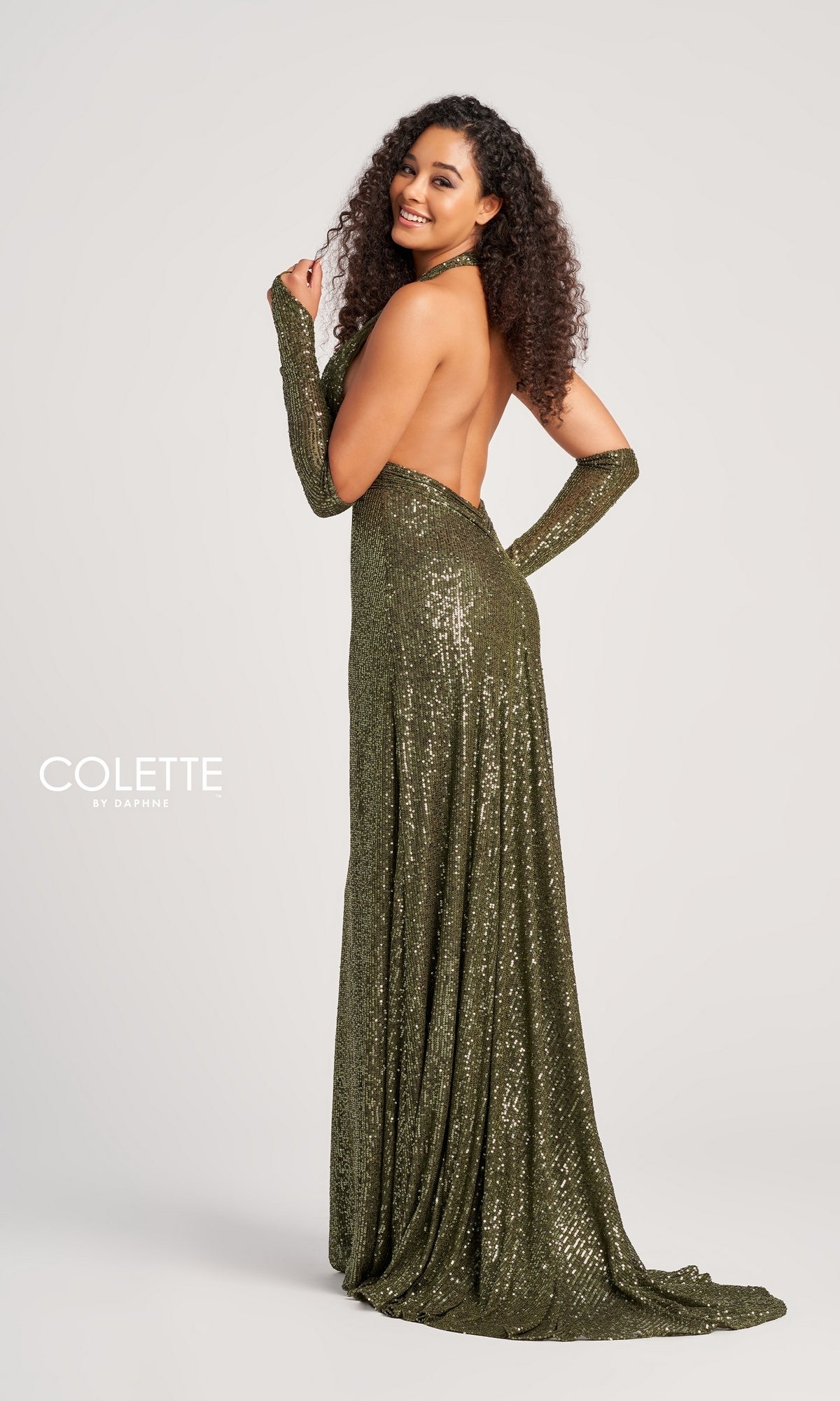 A woman with curly hair poses in the Colette Long Sequin Halter Prom Dress CL5115, its shimmering sequins catching the light. She stands against a plain background, with