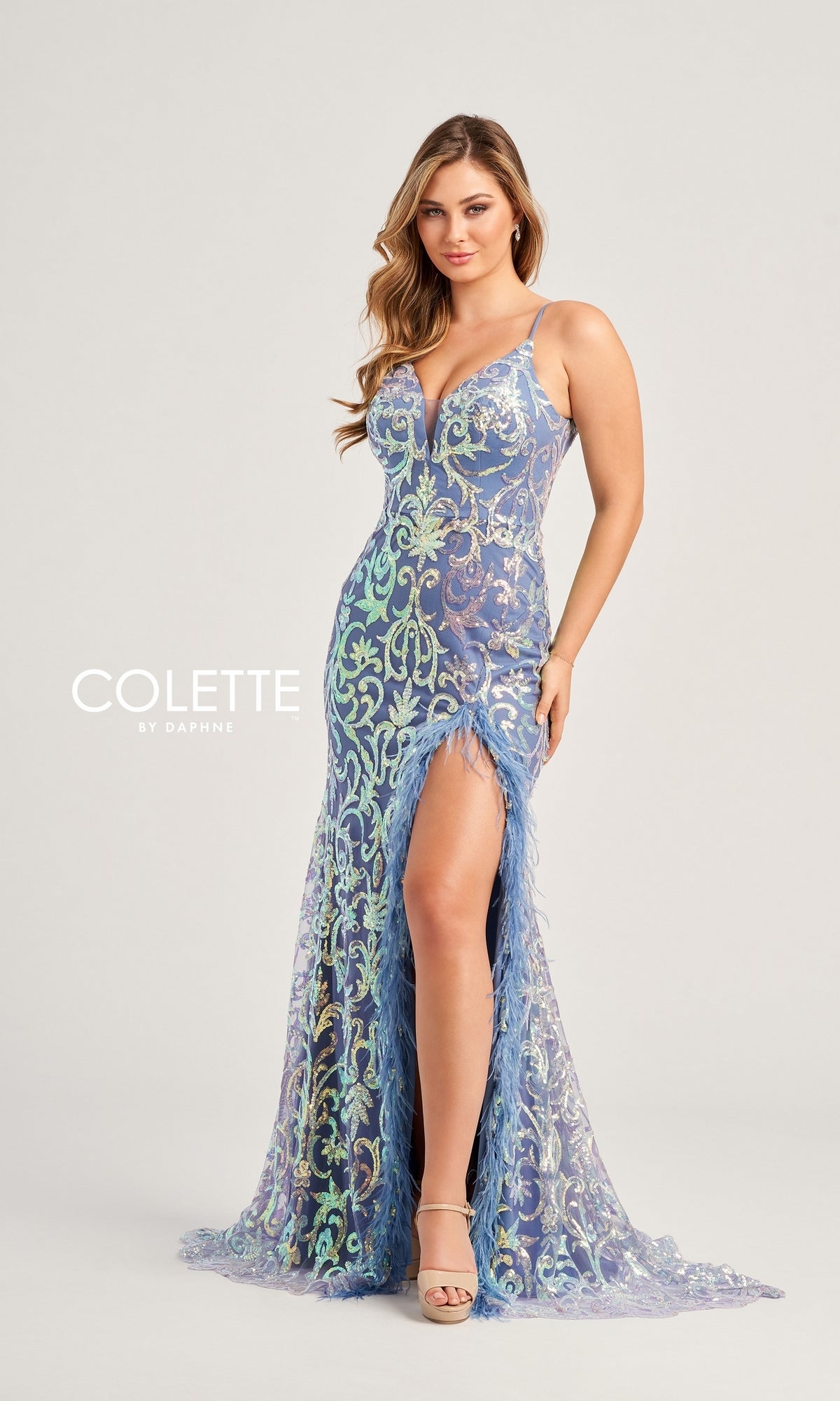 A woman models the Feather-Sequin Colette Long Prom Dress CL5155—fitted, floor-length, with blue and green sequins, a thigh-high slit, and thin straps—against a plain light background.