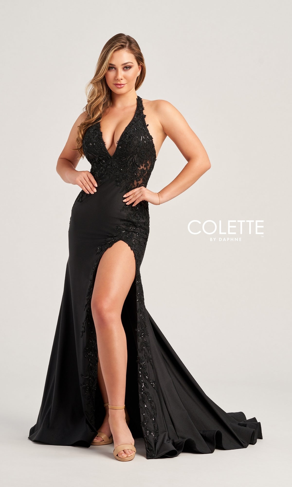 A woman stands against a plain background in the Lace-Bodice Colette Long Halter Prom Dress CL5206, featuring a high slit and sparkly lace with sequin details.