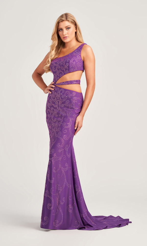 A woman wears the Colette Sheer-Waist One-Shoulder Prom Dress CL5281, a floor-length fitted purple gown with rhinestone details, side cutouts, and an asymmetric neckline, standing against a plain background.