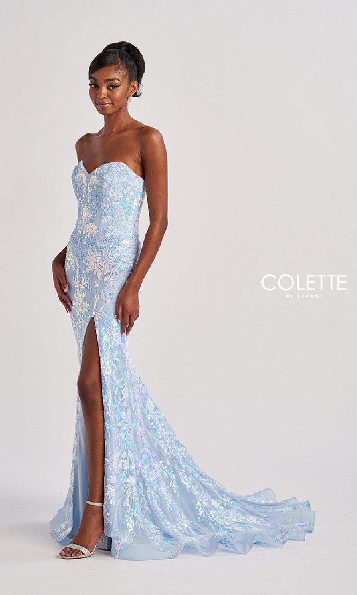 A woman models the Long Prom Dress: Colette CL8440—a strapless, light blue floral gown with a boned corset bodice and thigh-high slit—standing against a plain background. The