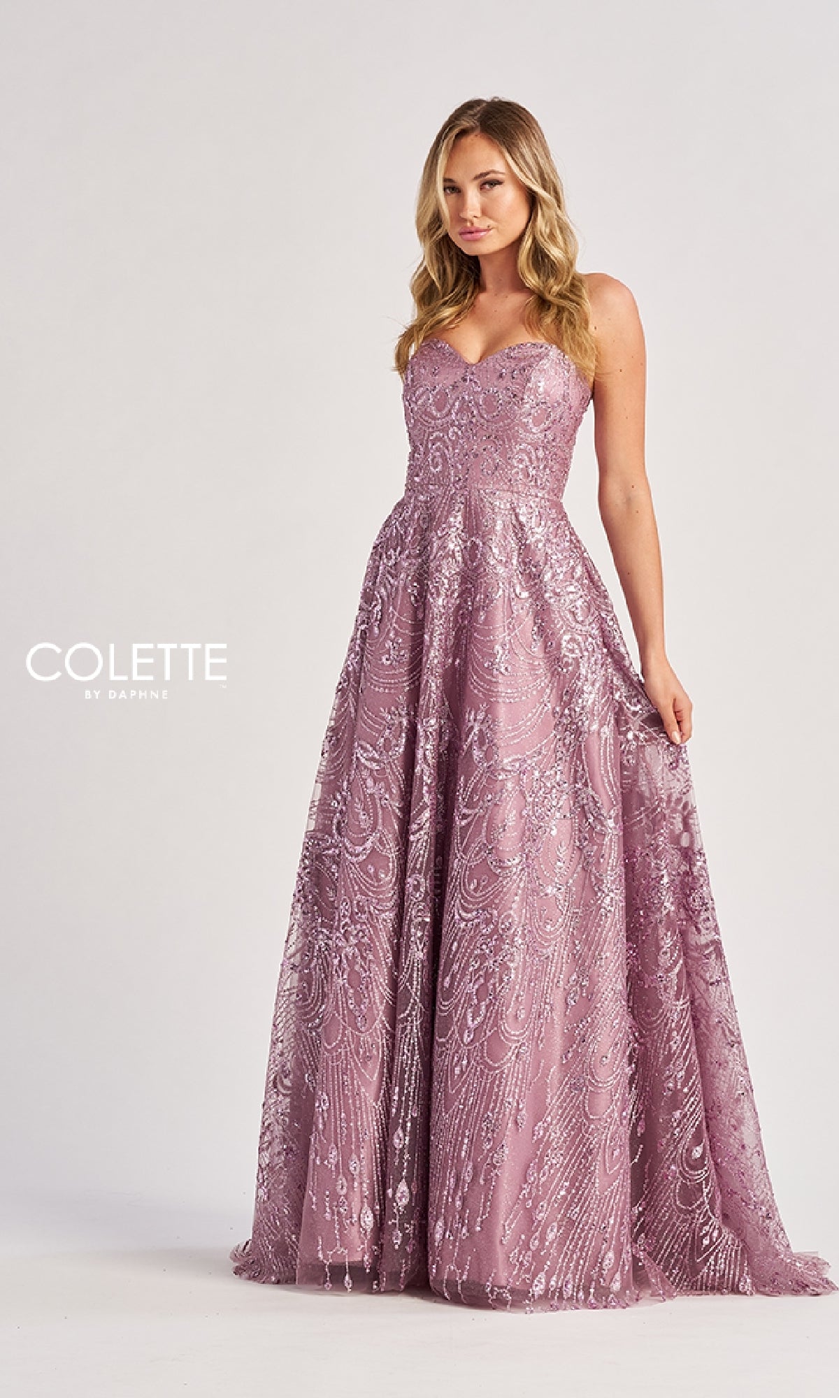 A woman stands against a plain background in the Colette CL8625 Long Prom Dress, featuring a strapless fitted bodice, intricate sequin detailing, a flared skirt, and shimmering accents for timeless glamour.