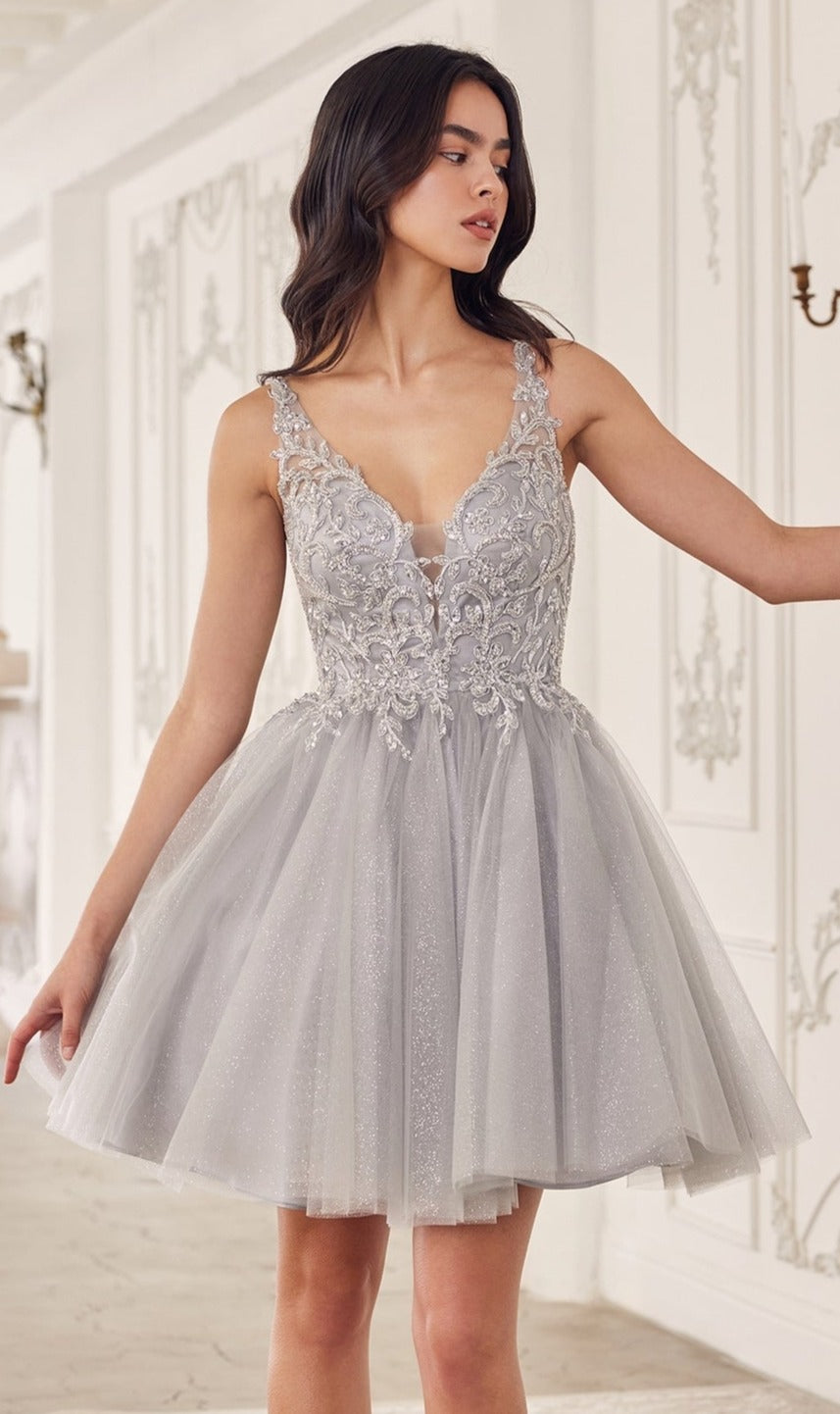 A woman stands in an elegant, light-colored room wearing the Lace-Up Short A-Line Homecoming dress CY022, featuring a silver-gray hue, floral lace details, and a deep V-neckline.