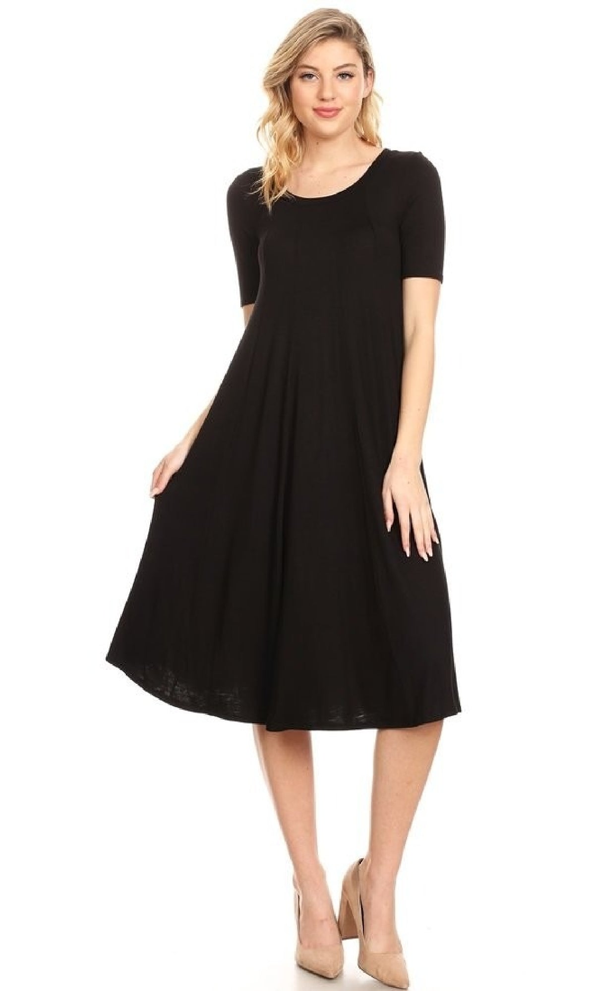 A woman models the Short Sleeve Casual Oversized Jersey Knit Dress, a loose-fitting black knee-length piece with short sleeves, paired with beige high heels against a white background.