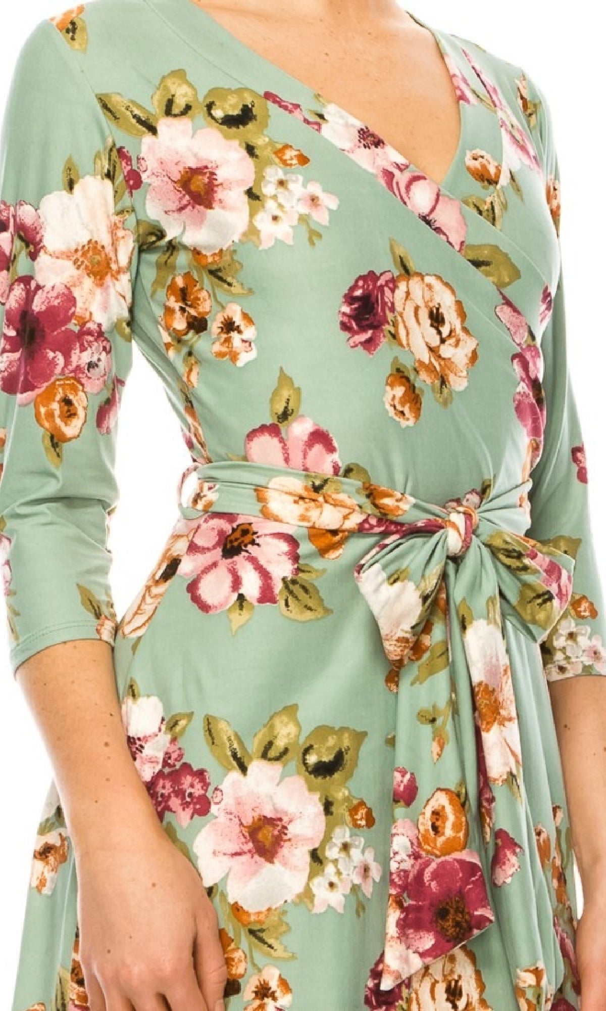 A woman wearing the Sage Green Floral Print Faux-Wrap Casual Dress featuring a side tie belt, three-quarter sleeves, and a flattering v-neckline.