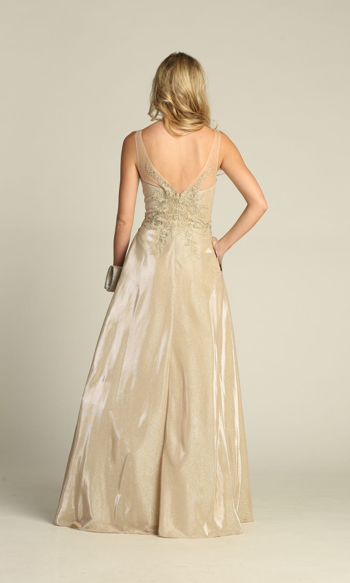 A blonde woman faces away from the camera, holding a small clutch and wearing the affordable Chicas DM4017 Lace-Bodice Long Glitter Prom Dress in champagne, which features a sleeveless, floor-length design and a V-shaped back.