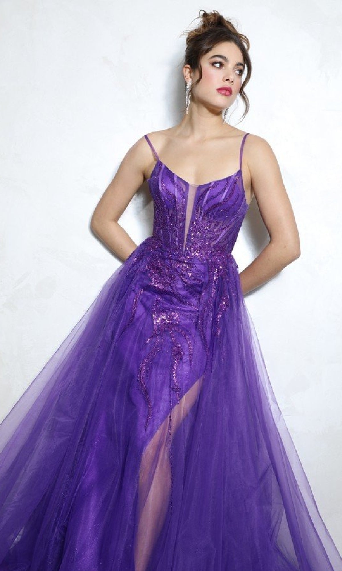 Woman wearing the Eureka EK112 Overskirt Long Sequin Prom Dress with sleeveless design and sequin accents stands against a plain light-colored wall, gazing to the side.