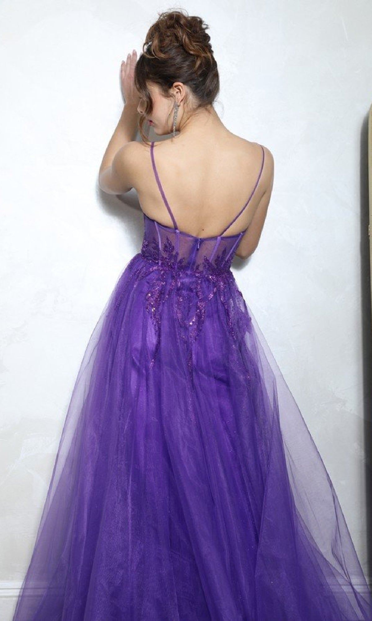 Woman wearing the Overskirt Long Sequin Prom Dress: Eureka EK112 stands with her back to the camera, facing a white wall.