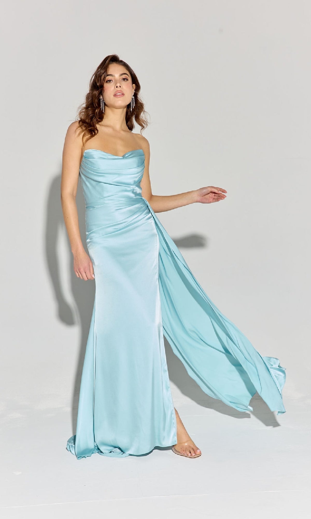 A woman wearing the Eureka EK118 Strapless Long Satin Prom Dress in light blue with a side drape stands against a plain light background.