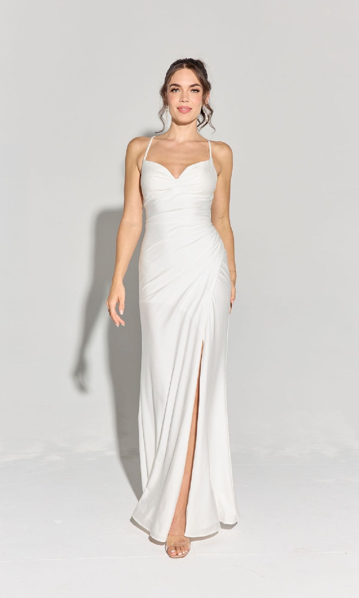 A woman wears the Classic Long Satin Prom Dress: Eureka EK136, featuring a white satin fabric, sweetheart halter neckline, ruched waist, and thigh-high slit, standing against a plain light background.