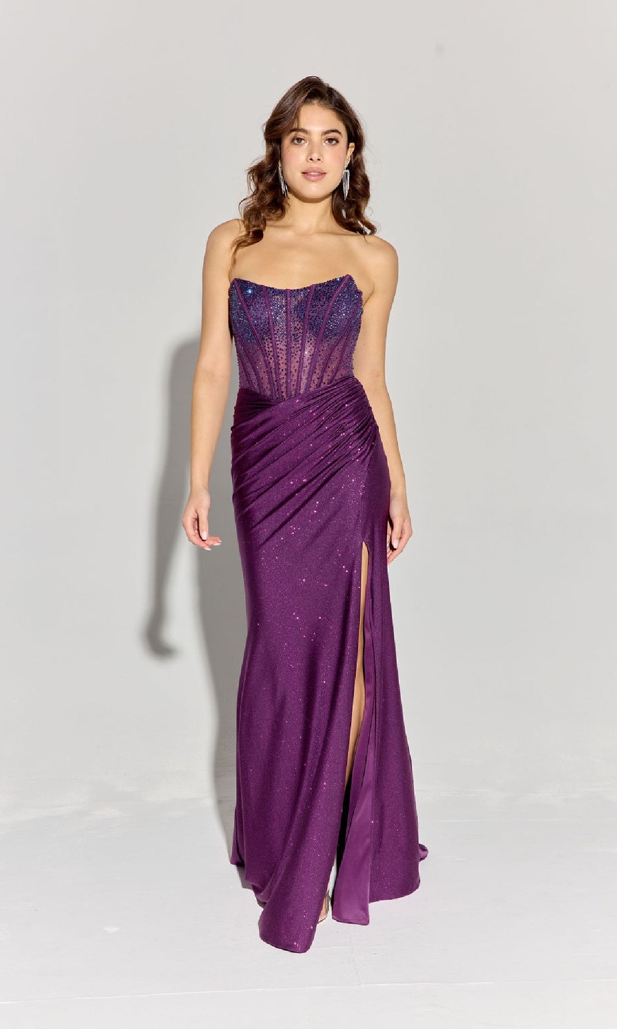 A woman poses against a plain light background in the Strapless Beaded Long Prom Dress: Eureka EK169, featuring a floor-length design with a sheer corset bodice, ruched skirt, thigh-high slit, and subtle sparkles.