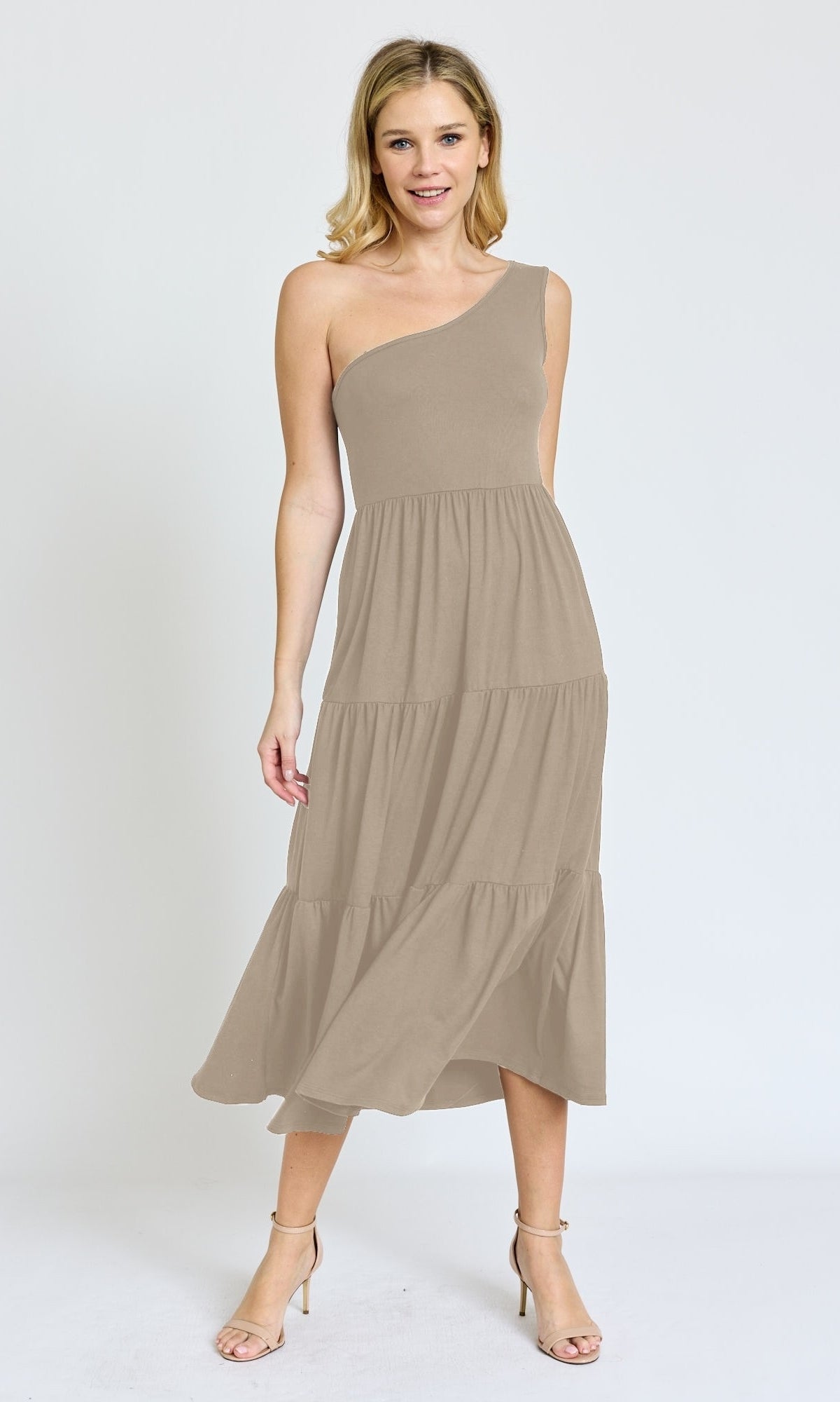 A woman stands against a plain white background wearing the One-Shoulder Casual Everyday Midi Dress in taupe, featuring a tiered midi silhouette and paired with ankle-strap heels.
