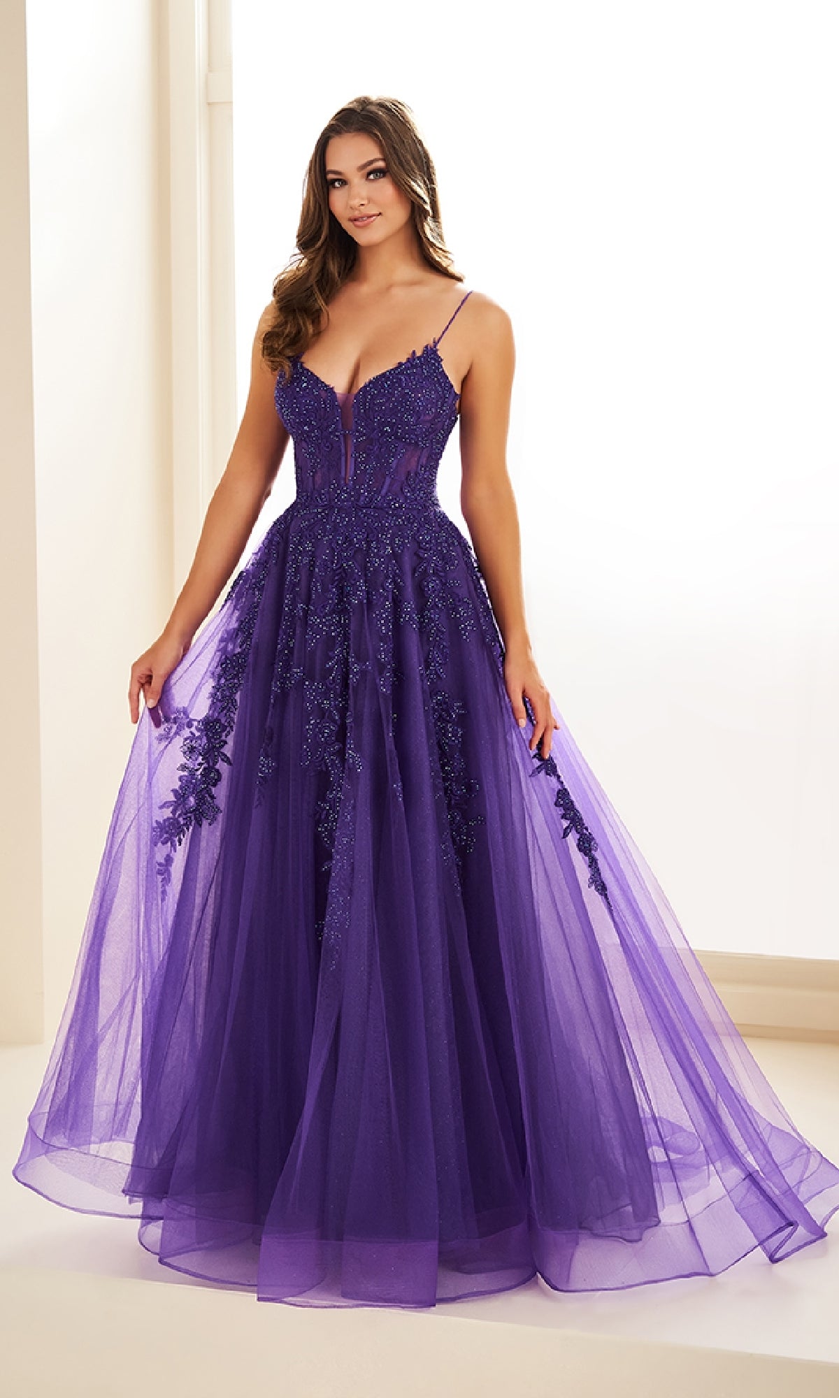 A woman wears the Sheer-Corset Long Lace Prom Ball Gown EW34036—an elegant, floor-length purple tulle dress with thin straps and floral details—standing indoors against a neutral background.