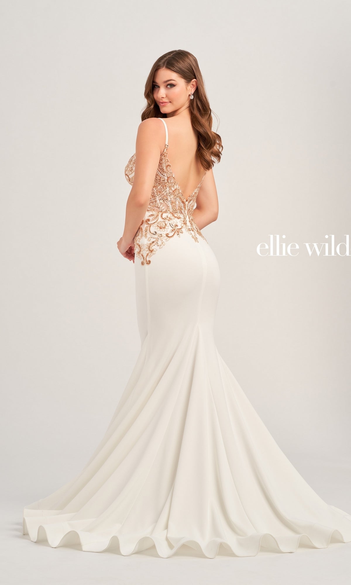A woman models the Ellie Wilde Beaded Long White Formal Dress EW35078, which features a gold beaded lace bodice and open back, against a plain light background. The words