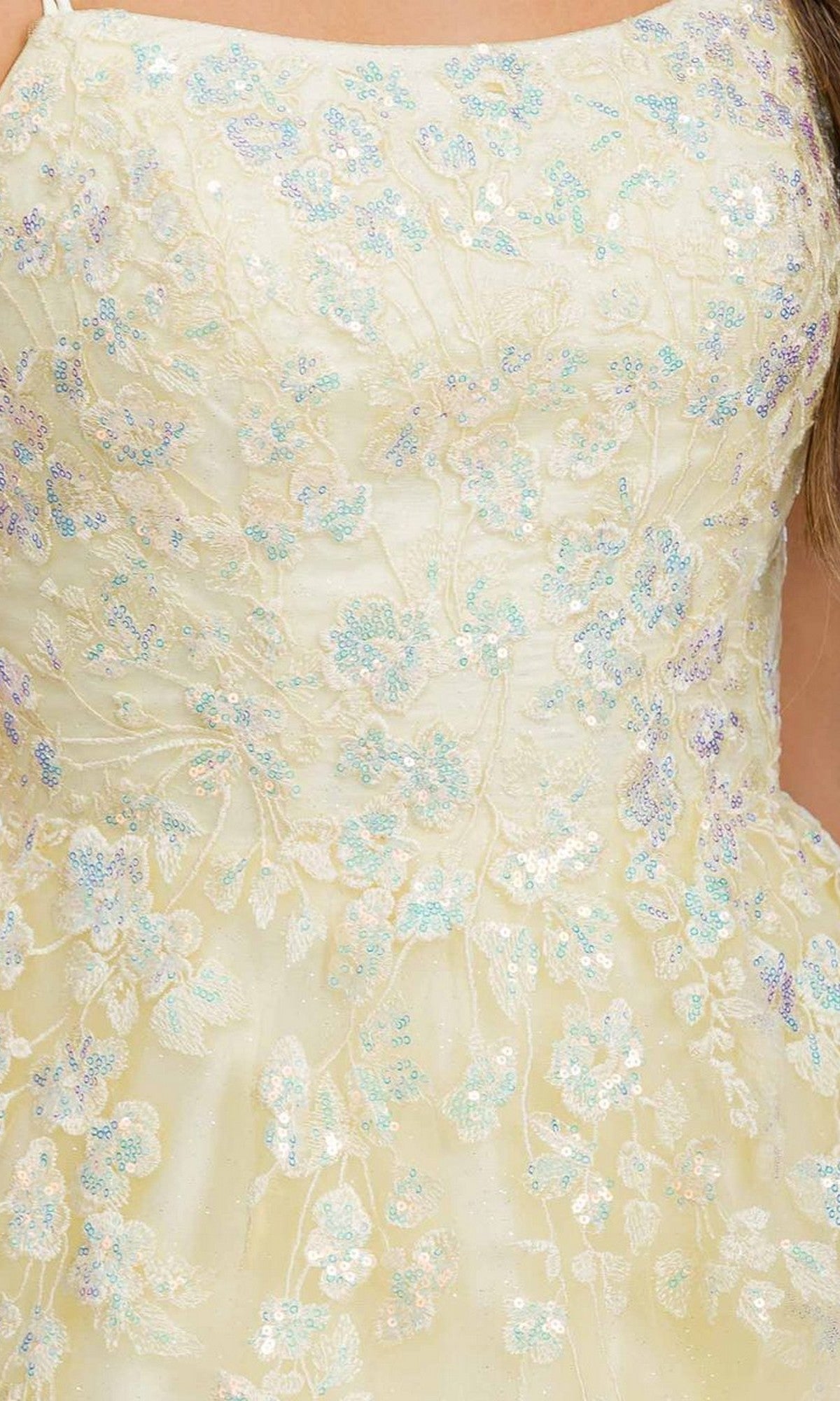 Close-up of the Eureka EK197 long prom dress in light yellow, featuring shimmering fabric, iridescent floral embroidery, sequin details, and delicate lace appliques on the bodice.