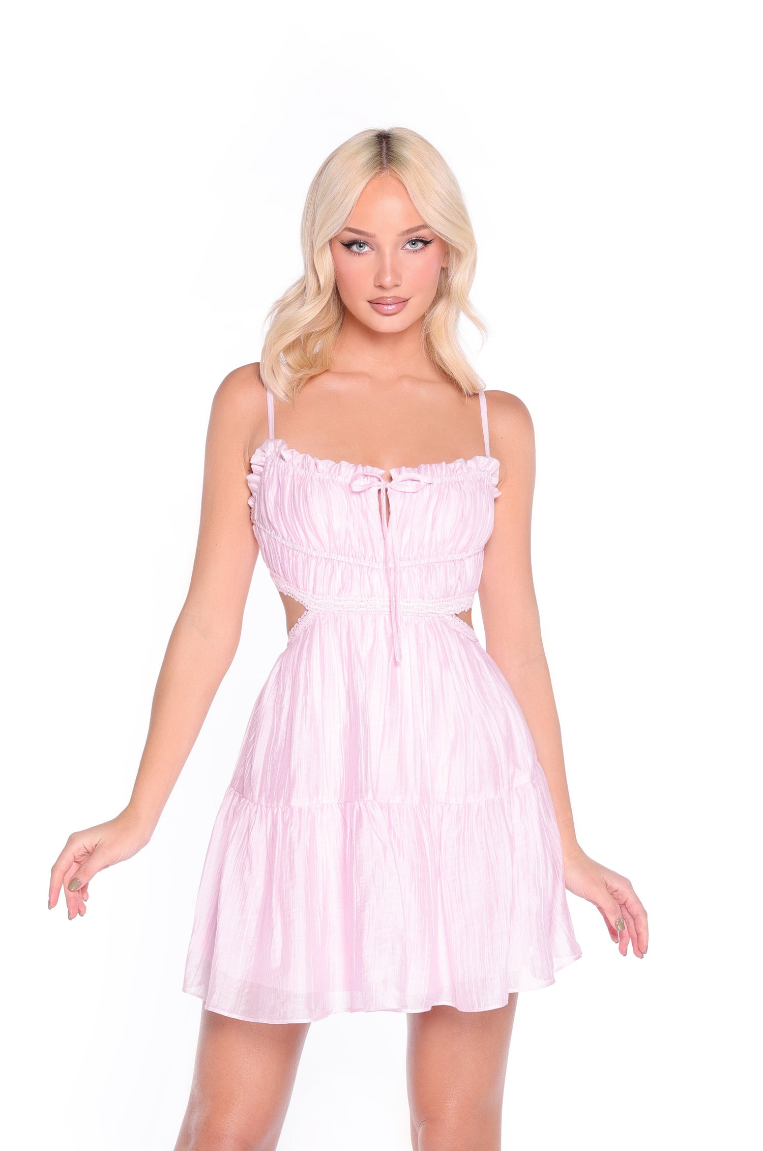 A woman with long blonde hair models the Elara Pink Open-Back Casual Summer Dress, which features a fitted bodice, ruffled tiers, and an a-line skirt, as she poses against a plain white background.