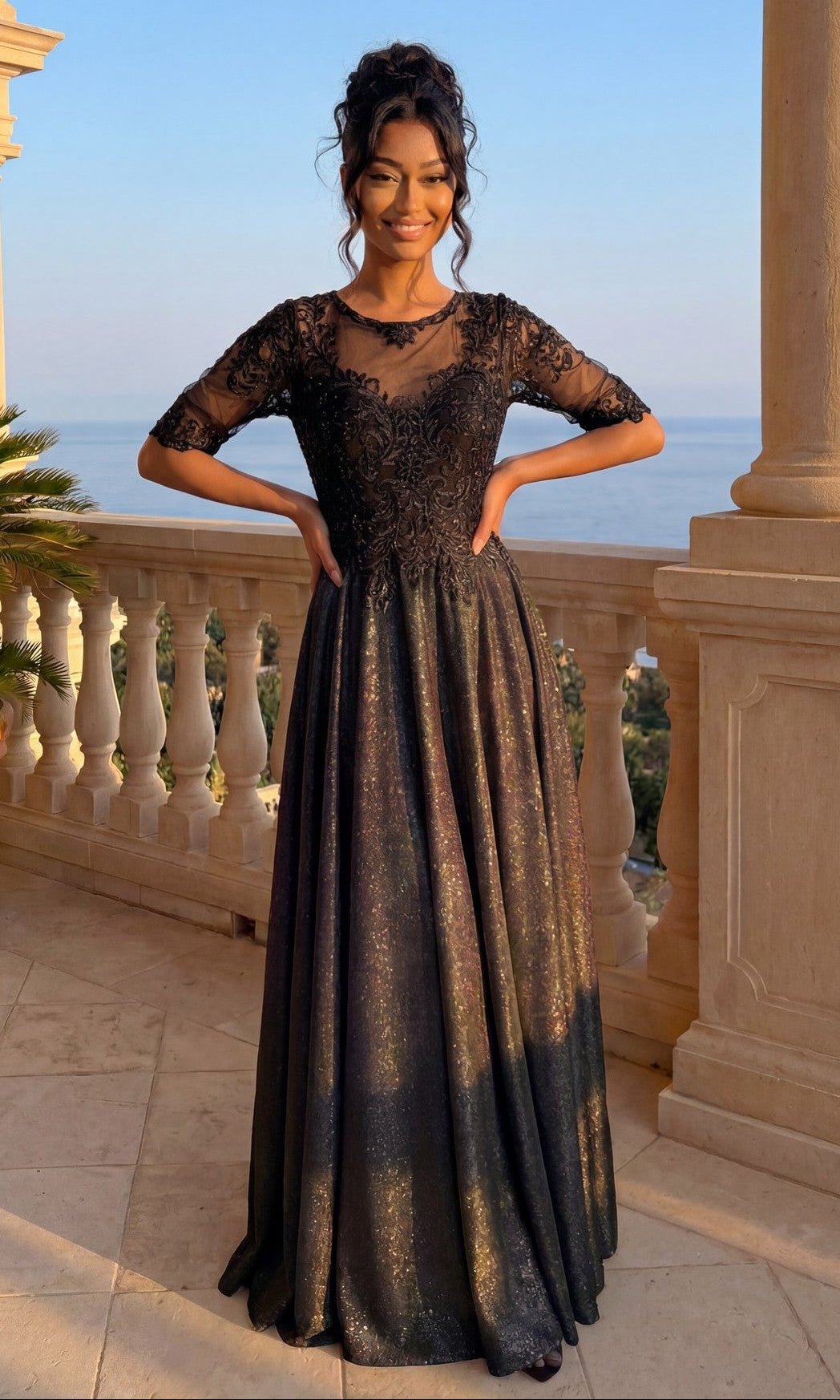 A woman stands on a balcony in the Long Formal Dress: Chicas J006, a black lace gown with sheer sleeves, hands on hips and smiling against a scenic backdrop of trees and water.