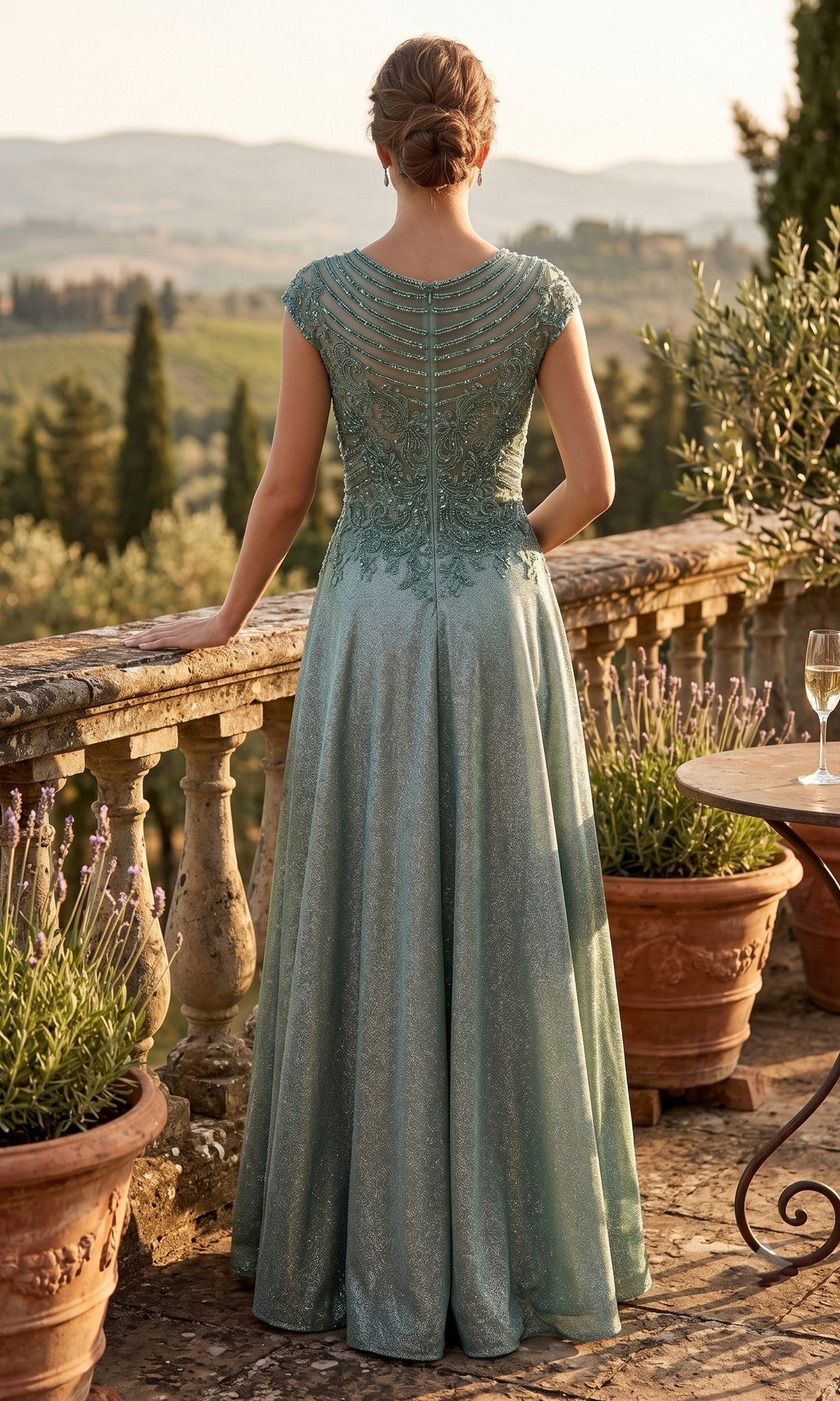 A woman wears the Long Prom Dress: Chicas J132, featuring an elegant formal design with a sparkling A-line skirt and embellished bodice, as she stands on a stone terrace with potted plants overlooking a scenic, sunlit landscape.