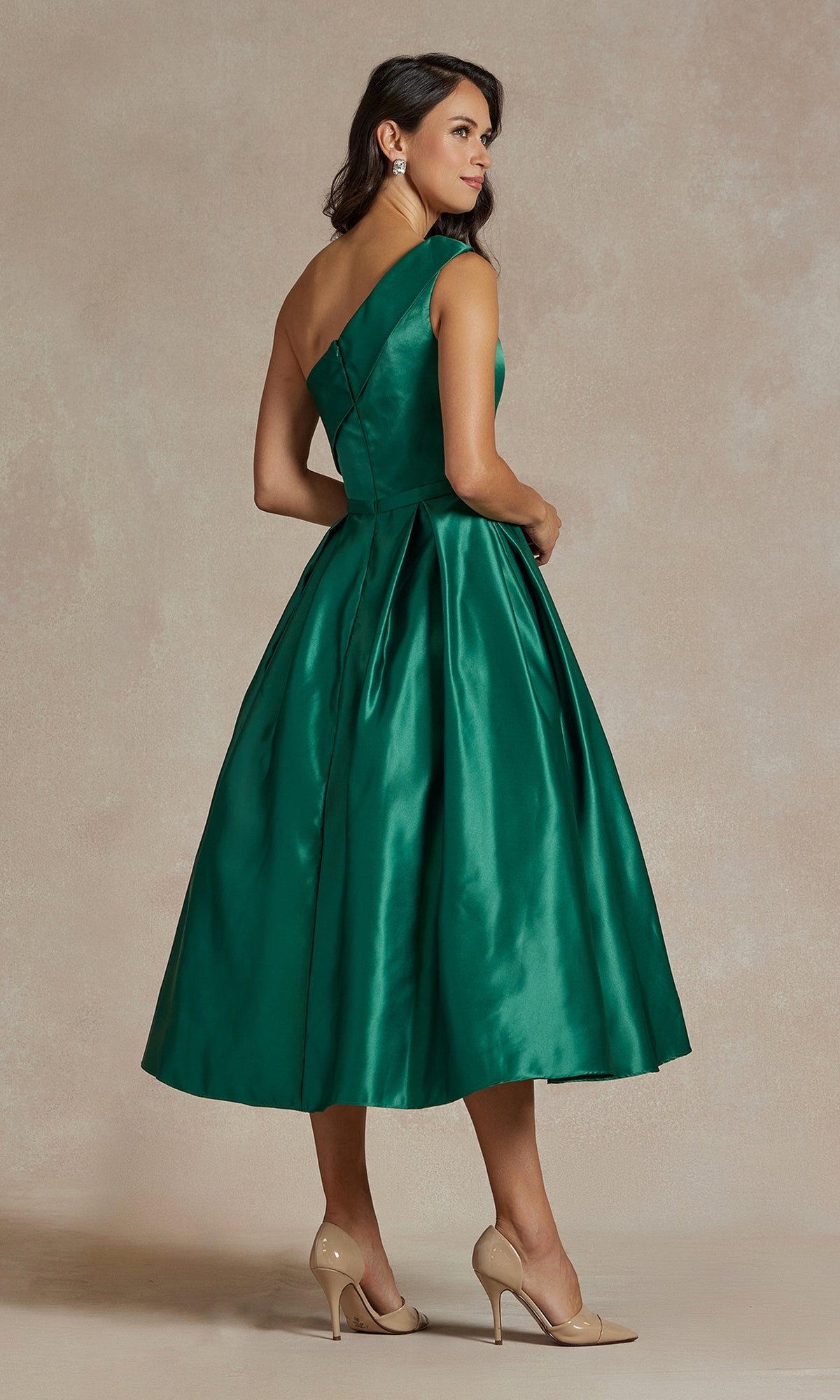 A woman models the One-Shoulder Simple Tea-Length Party Dress JE931 in green, featuring a full skirt and elegant design, as she stands sideways in beige heels against a neutral backdrop.