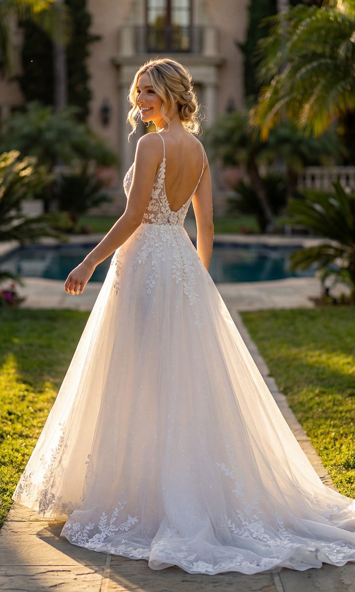 A woman stands outdoors on a path, looking over her shoulder with a pool and greenery in the background, wearing the Long Formal Dress: Juliet JT2633LW— a modern bridal gown featuring a white lace bodice and A-line tulle skirt.