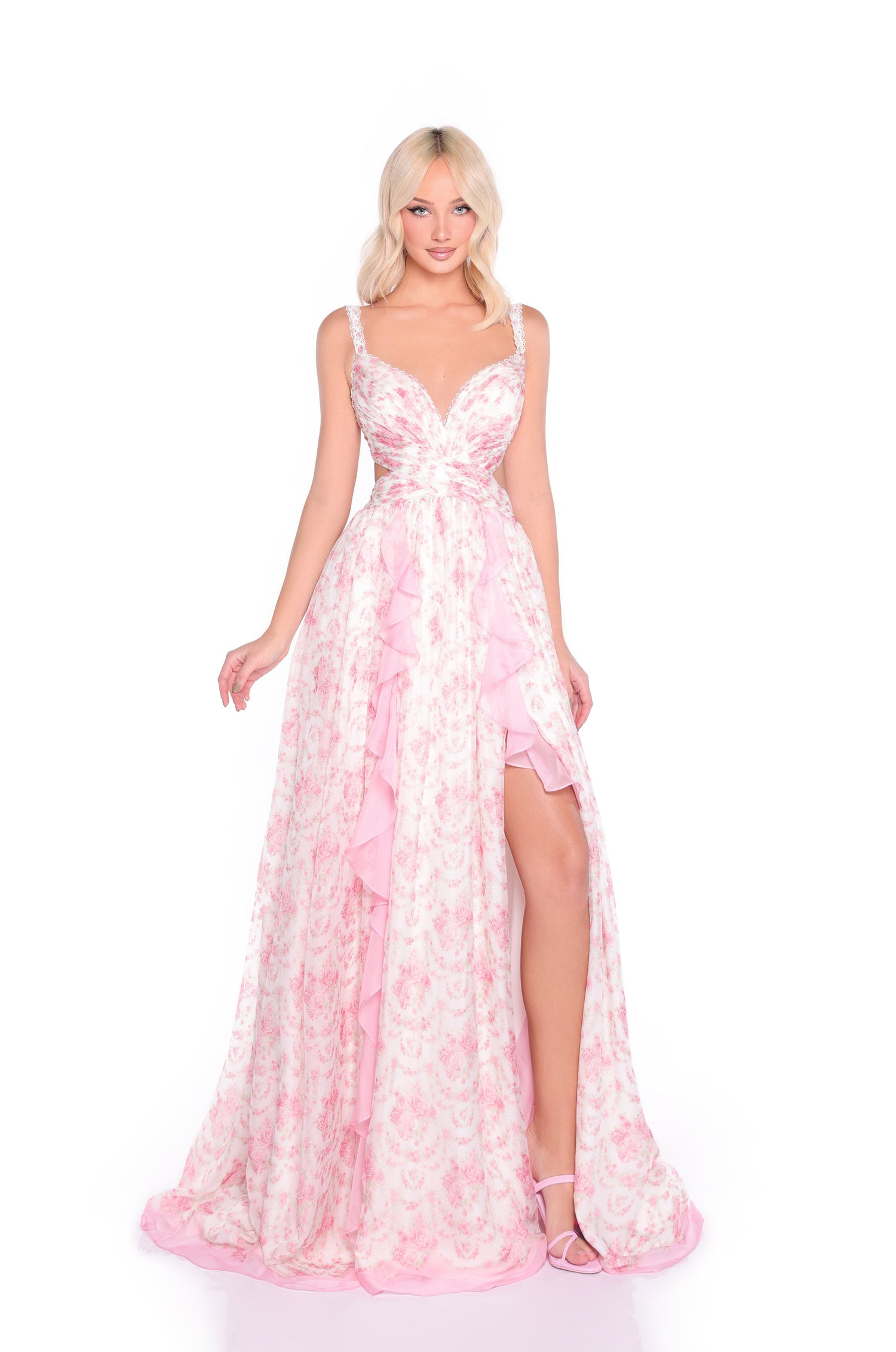 A woman wearing the Open-Back Pink Floral Maxi Dress: Juliette, featuring ruffled layers and a thigh-high slit, stands against a white background.