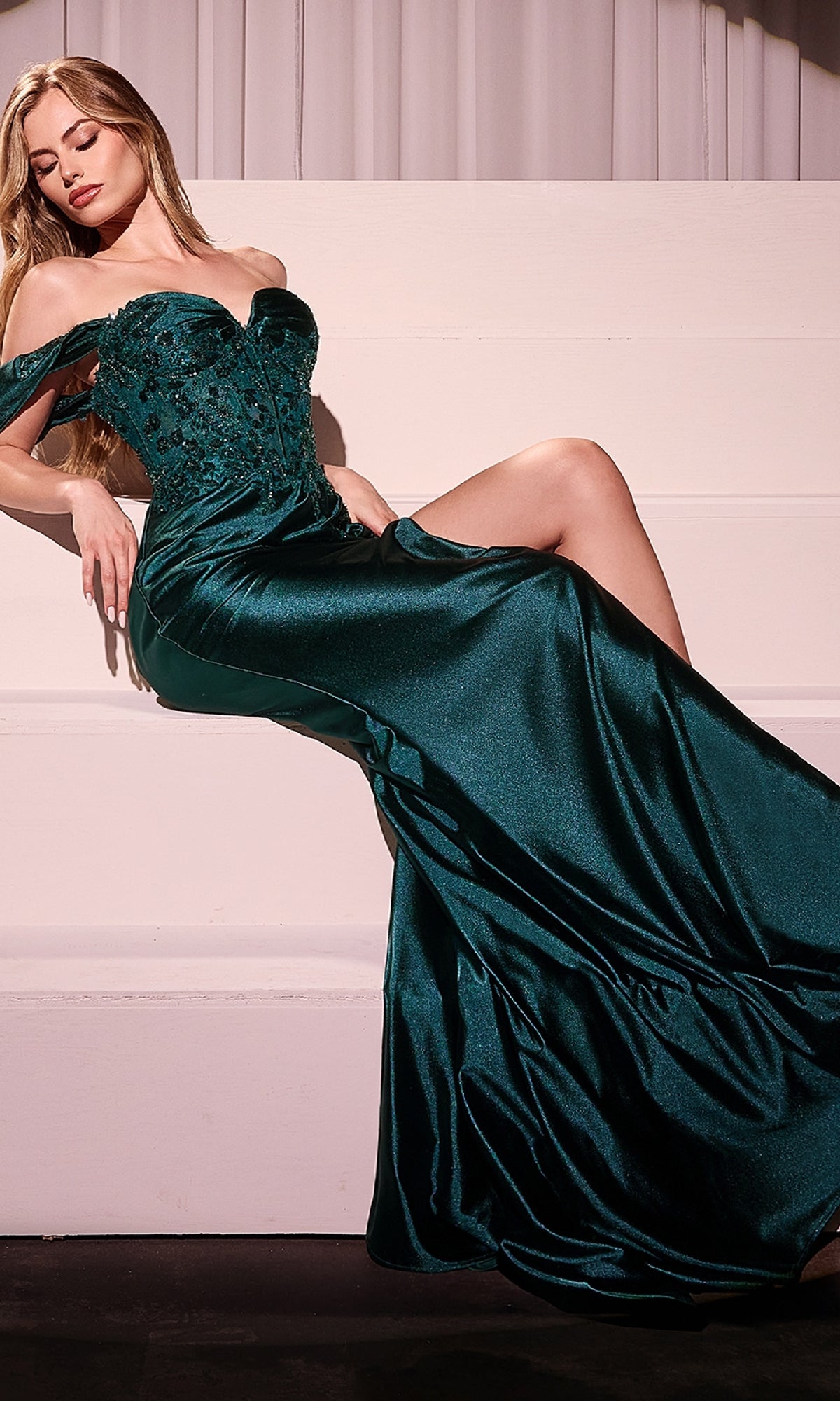 A woman in the Off-Shoulder Long Satin Prom Dress: Ladivine KV1121 with floral bodice details reclines gracefully on white steps.