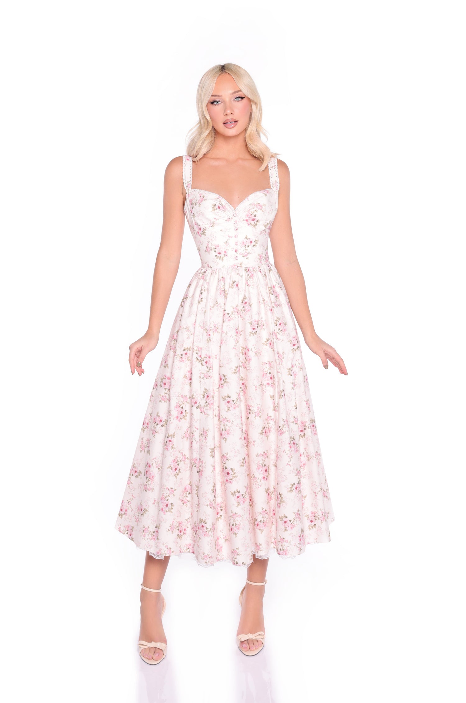 A person wears the Cream Floral Print Casual Midi Dress: Liora, featuring a fitted bodice and flared midi skirt, paired with strappy high-heeled sandals, standing against a white background.