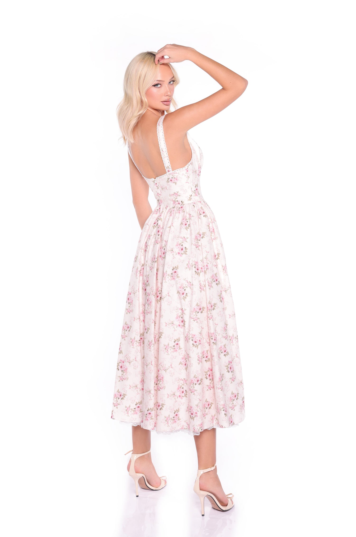 A woman with blonde hair wears the Cream Floral Print Casual Midi Dress: Liora, pairing it with high-heeled sandals as she poses backward, looking over her shoulder against a white background.