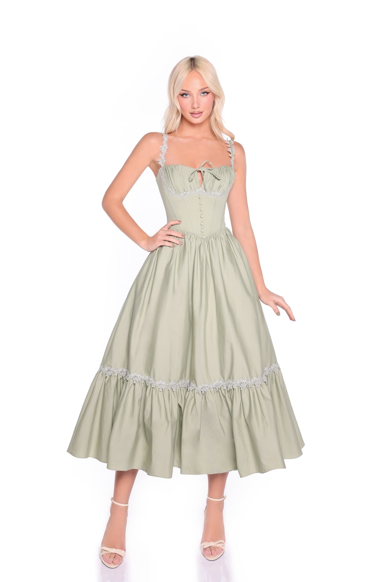 A woman models the Sage Green Casual Midi Dress: Lioren, featuring a sleeveless corset bodice, flared skirt, and ruffled design, as she stands against a white background.