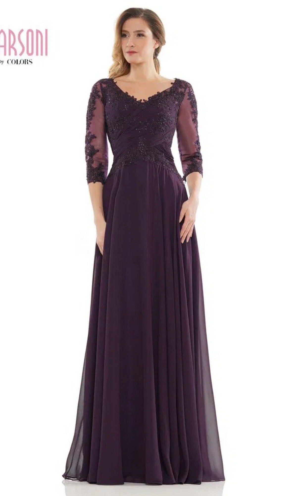 A woman wearing the Marsoni M237 long formal dress in eggplant, featuring an a-line silhouette, floor length, sheer three-quarter sleeves, and an elegant lace applique bodice.