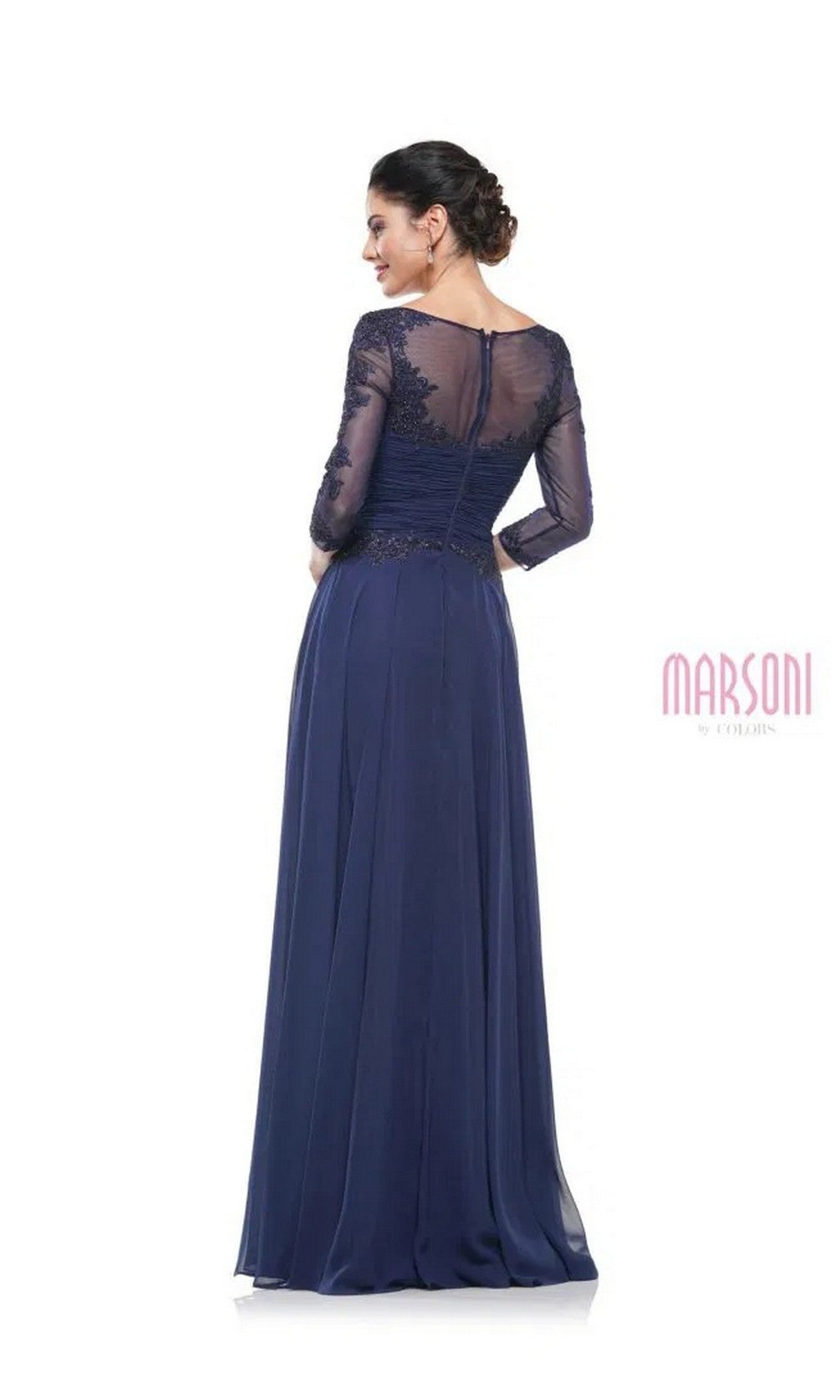 A woman stands gracefully with her back to the camera, wearing the Marsoni M237 long formal dress—an elegant navy blue A-line gown with sheer lace sleeves, lace applique bodice, and a sheer lace back.