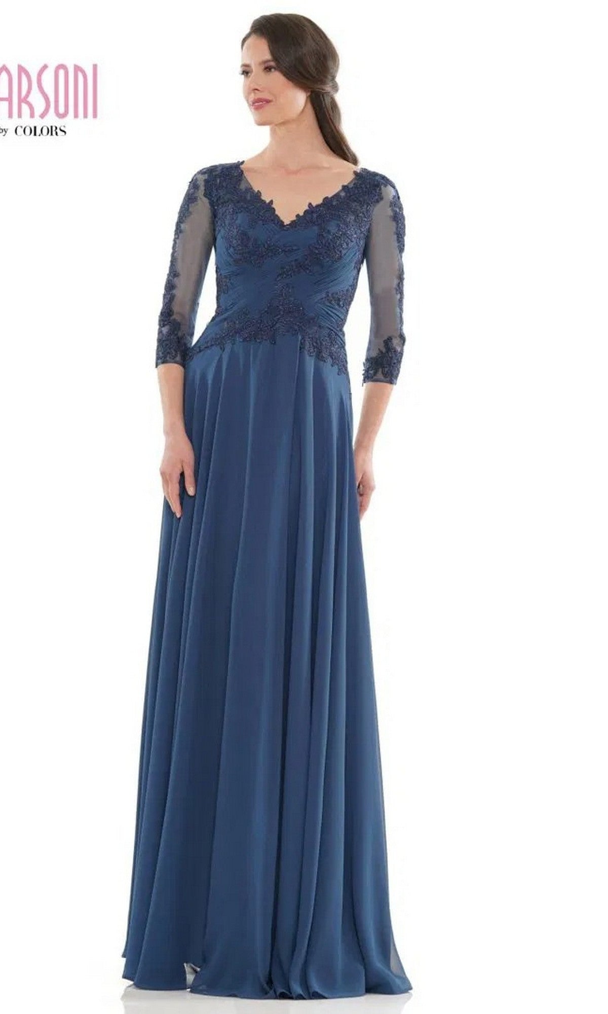 A woman wearing the Marsoni M237 long formal dress in peacock, featuring an A-line silhouette, lace applique bodice, and three-quarter sleeves, stands against a plain white background.