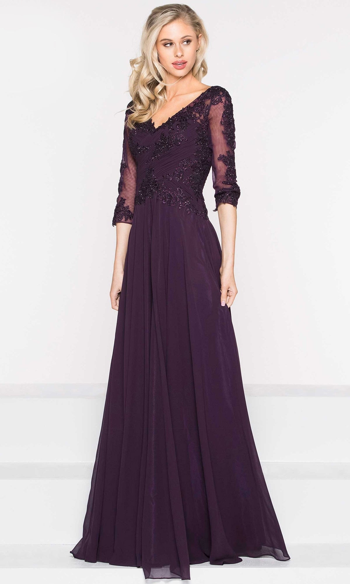 A woman poses in the Long Sleeve Long A-Line Formal Dress: Marsoni M237, a deep purple gown with sheer lace sleeves and floral embroidery.
