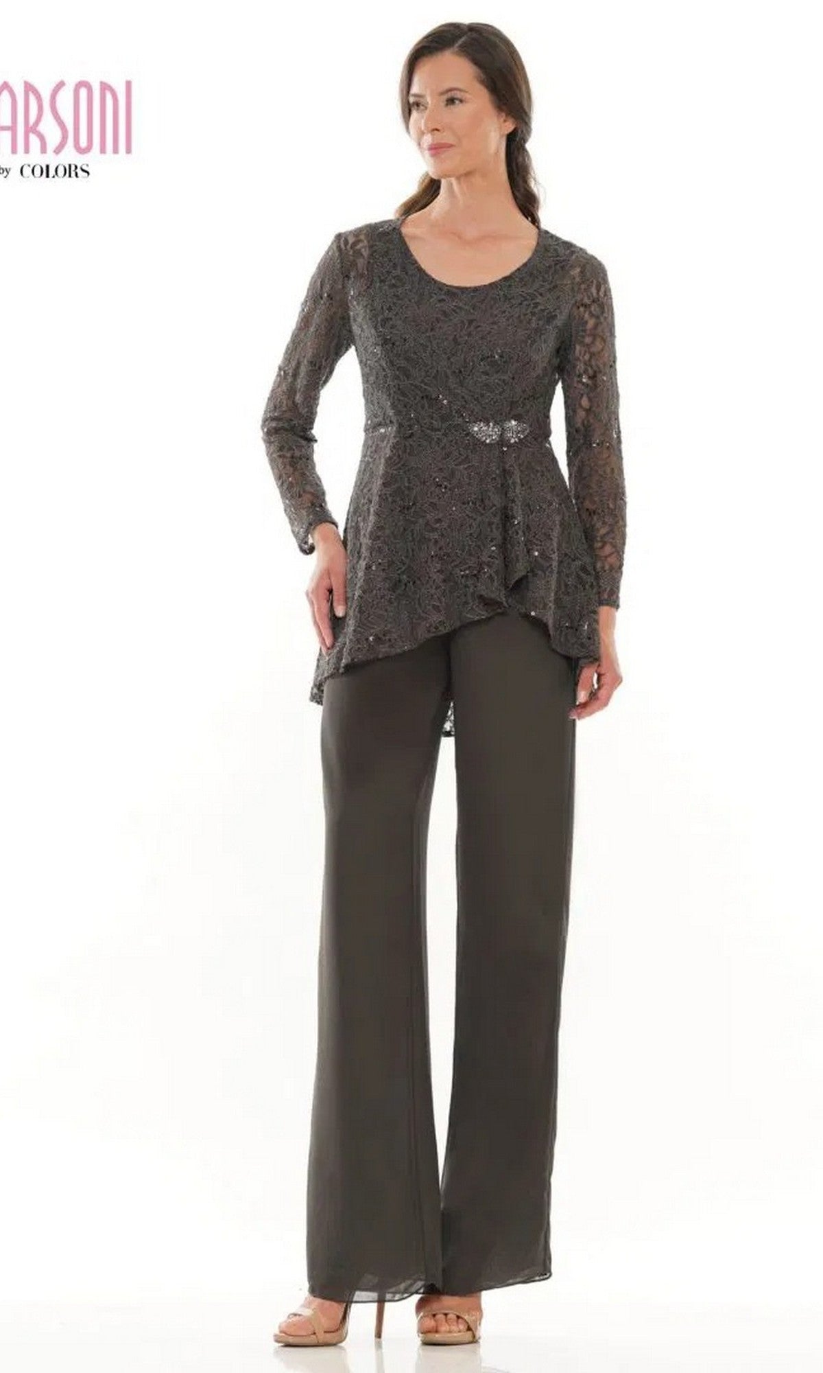 A woman stands against a white background wearing the Marsoni M305 long formal pantsuit in charcoal, featuring a dark lace jacket with long sleeves and an asymmetrical hem, paired with wide-leg chiffon pants and sandals.