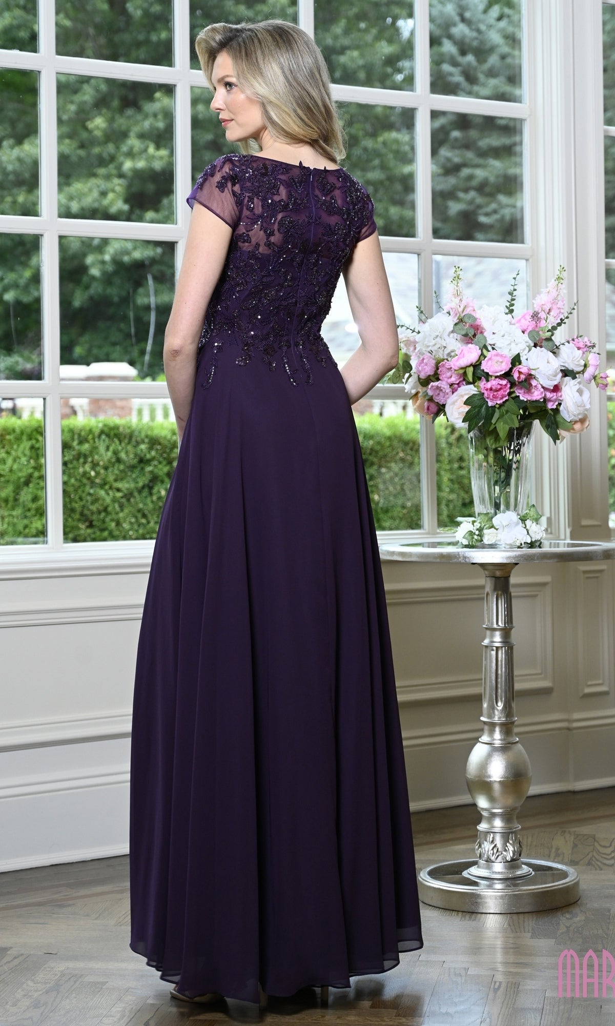 A woman seen from behind wearing the Modest Long Formal Dress: Marsoni M360, a dark purple A-line evening gown with a sheer, beaded bodice and cap sleeves.