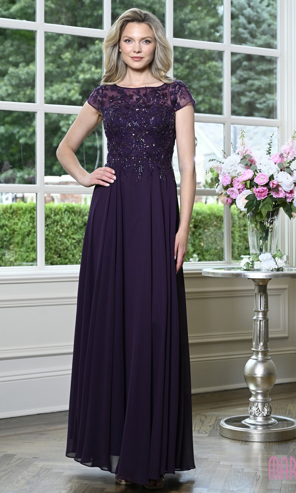 A woman wears a Modest Long Formal Dress: Marsoni M360, a floor-length, eggplant-colored beaded evening gown with cap sleeves and a pleated A-line skirt.