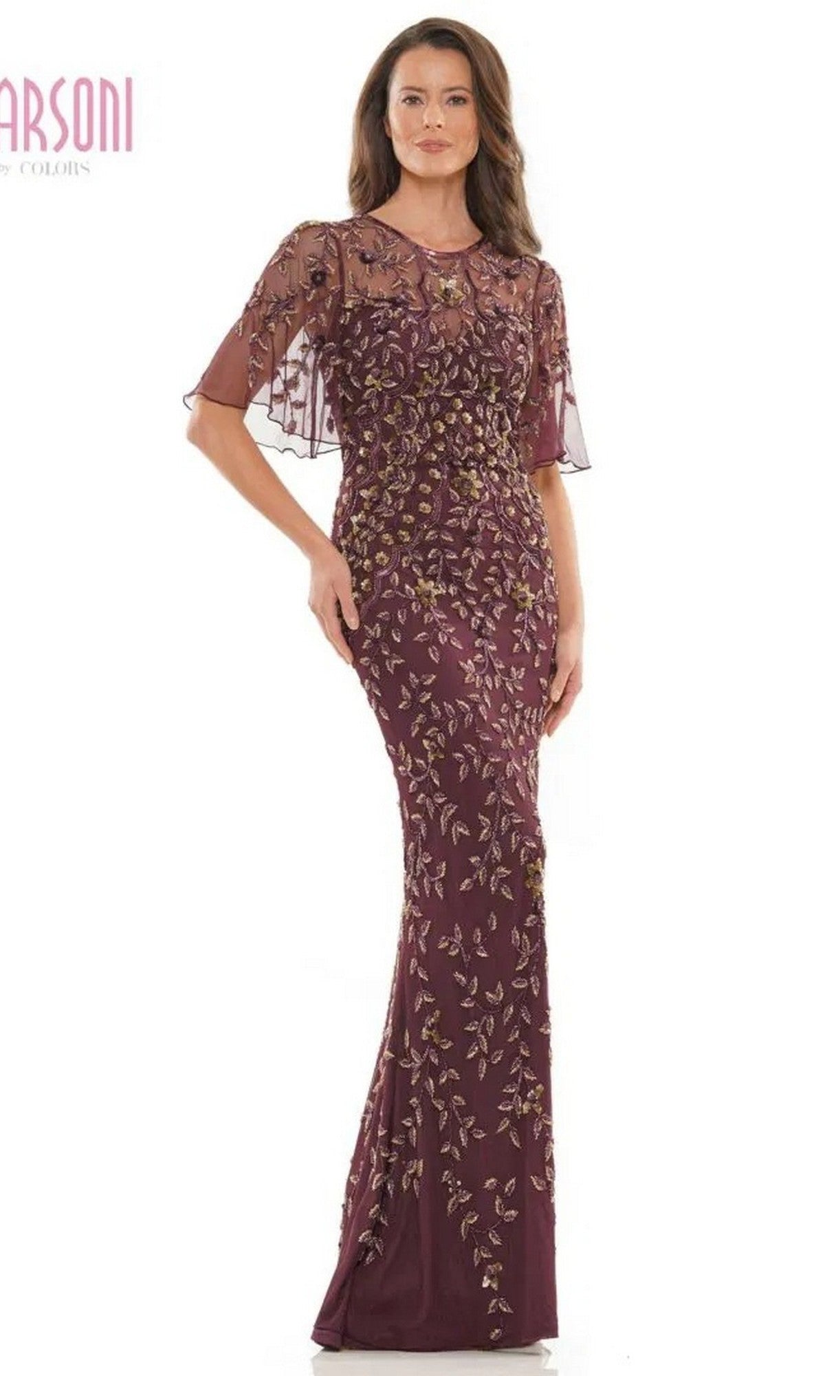 A woman wearing the Marsoni MV1208 long formal dress in eggplant and gold, featuring gold floral embroidery, sequin embellishments, and sheer short sleeves, stands against a white background.
