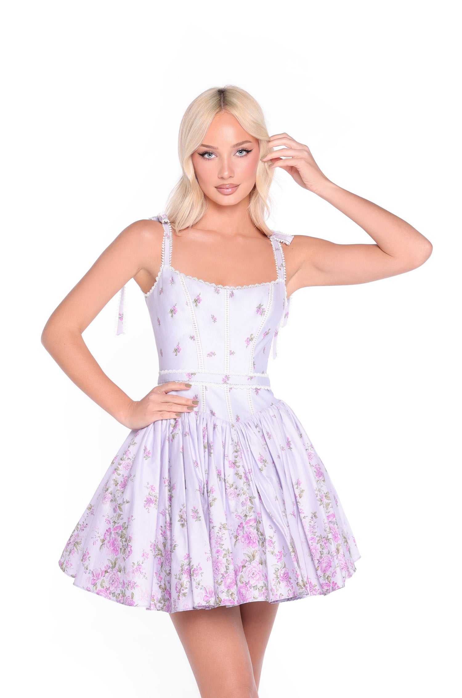 A woman with blonde hair wears the Lilac Floral Short Casual Dress: Mila, featuring a fitted bodice and flared skirt, standing against a white background.